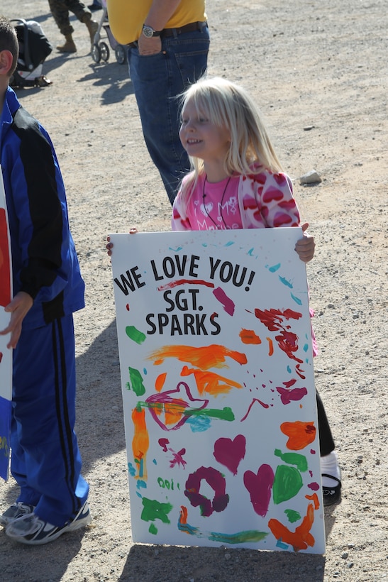 Four-year-old Destiny Sparks, daughter of Sgt. Heath Sparks, a training noncommissioned officer with Battalion Landing Team 1st Battalion, 7th Regiment, holds a sign she painted for her dad at the Del Valle soccer field Jan. 6, 2011. Destiny watches anxiously for the buses to arrive bringing her dad home after an eight-month-long deployment.