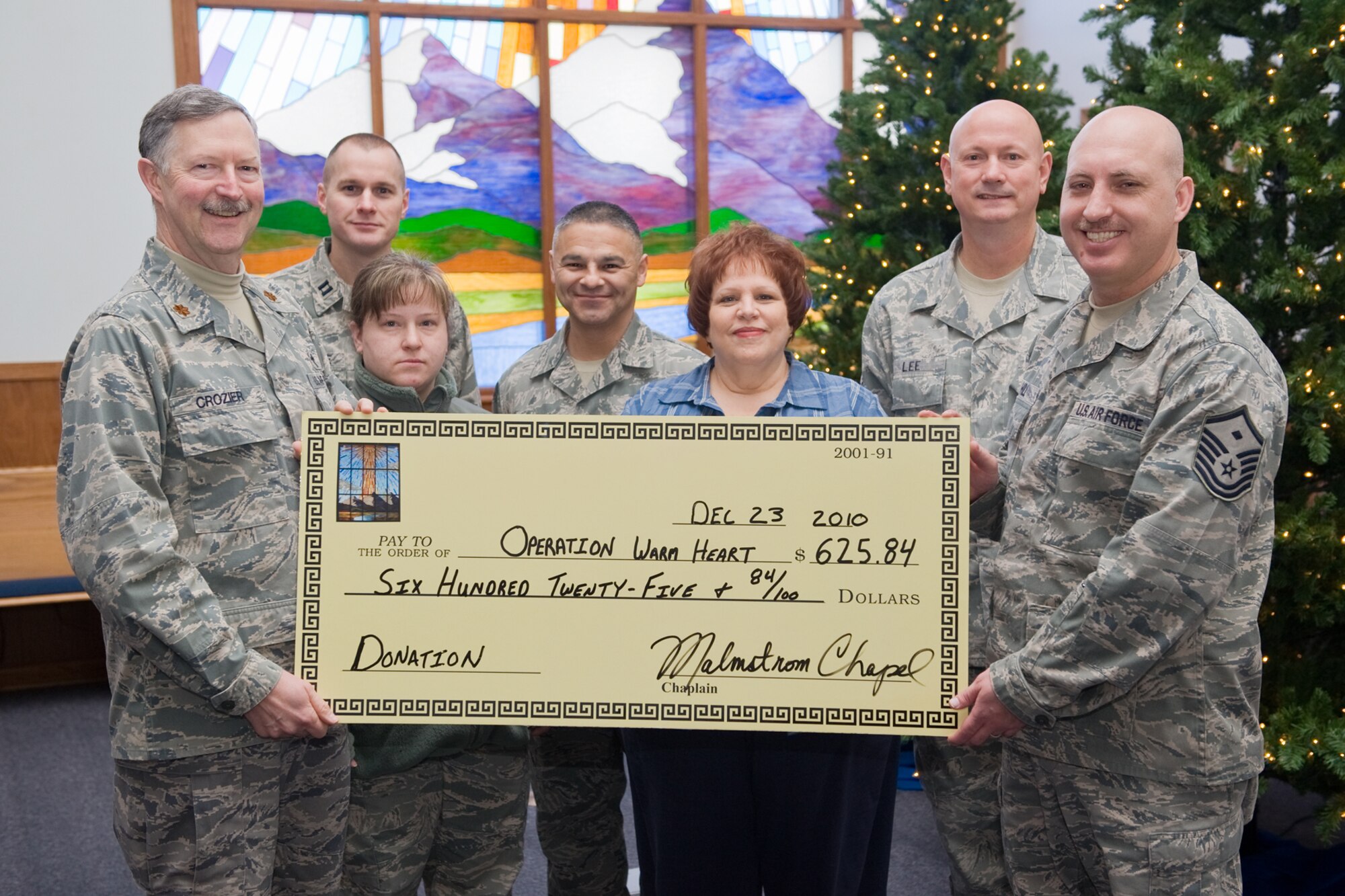 Members of the chapel staff donate a check for $625.84 to members of the first sergeant's council to be used for Operation Warmheart, a program that helps less fortunate military families during the holidays. From left to right are Chaplain (Maj.) Richard Crozier, Chaplain (Capt. ) Steven Survance; Tech. Sgt. Jennifer Fines; Master Sgt. Timoteo Silva; Jodene Antonson; Senior Master Sgt. Michael Lee; and Master Sgt. Jason Hill. (U.S. Air Force photo/Beau Wade)