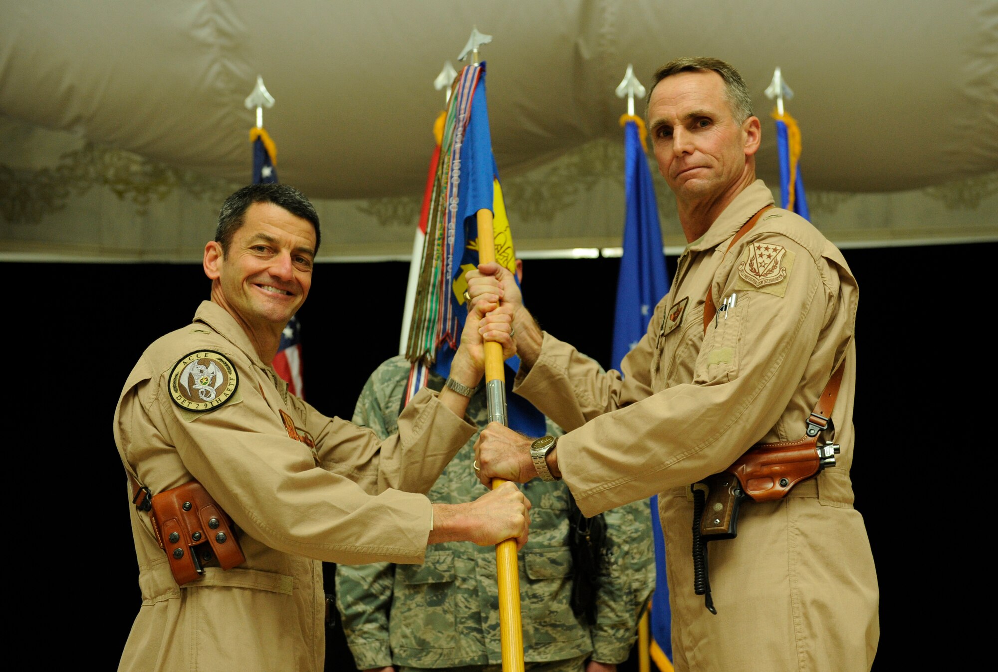 U.S. Air Force Brig. Gen. Russell Handy, Ninth Air and Space Expeditionary Task Force - Iraq commander, hands off the 321st Air Expeditionary Wing guidon to Brig. Gen. Anthony Rock, the new 321st Air Expeditionary Wing commander and Director of Iraq Training and Advisory Mission - Air Force, at Al Faw Palace in Victory Base Complex, Baghdad, Jan. 6. Rock most recently served as the Air Command and Staff College commandant and Spaatz Center for Officer Education vice commander. (U.S. Air Force/Staff Sgt. Levi Riendeau)