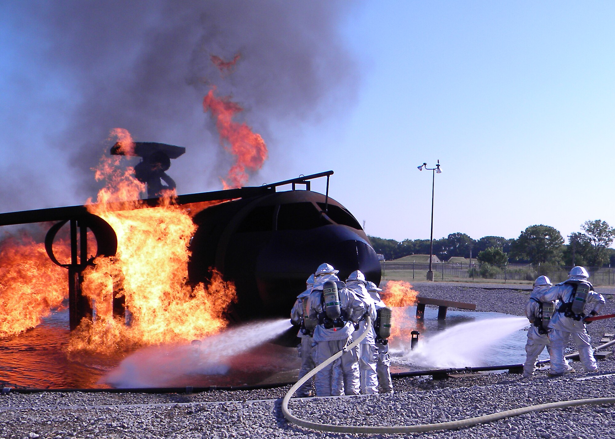 McConnell firefighters extinguish a fire utilizing the roll on method on an aircraft propane fire trainer at the fire training area Aug. 10, 2010, McConnell Air Force Base, Kan. Using the roll on method simulates applying a foam blanket to extinguish a running fuel fire. The aircraft propane fire trainer simulates multiple aircraft situations to include engine, landing gear, auxiliary power unit and interior fires. (courtesy photo)
