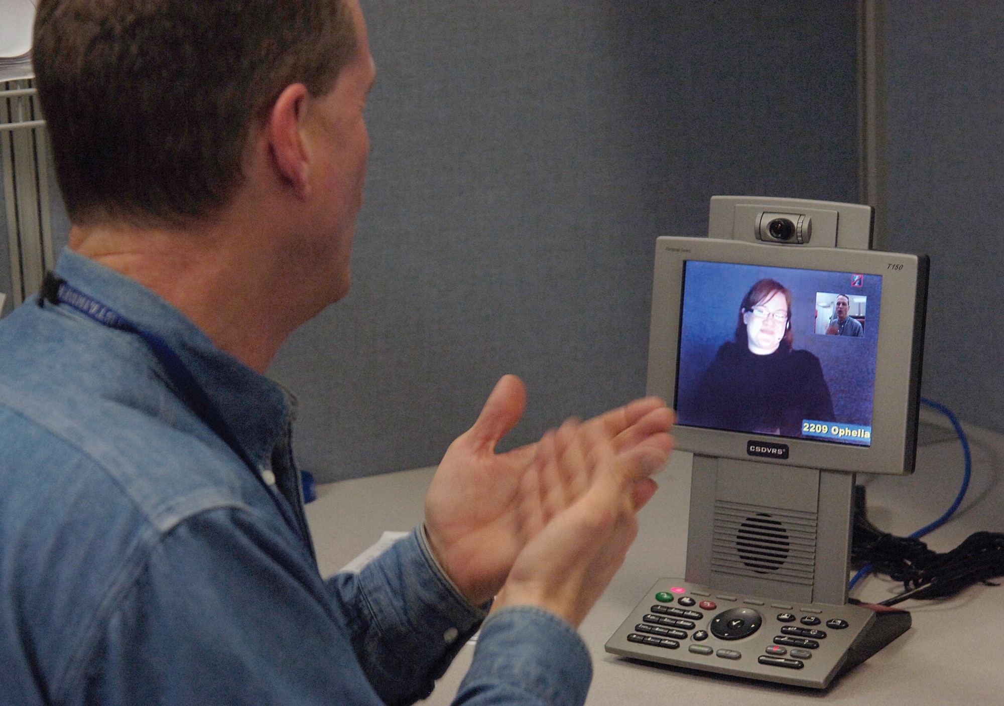 David Harman communicates by sign language to an interpreter on a new video phone, the first one in use at Tinker. Mr. Harman, with the 948th Supply Chain Management Group, loves the independence and increased work efficiency the new phone offers. (Air Force photo by Margo Wright)