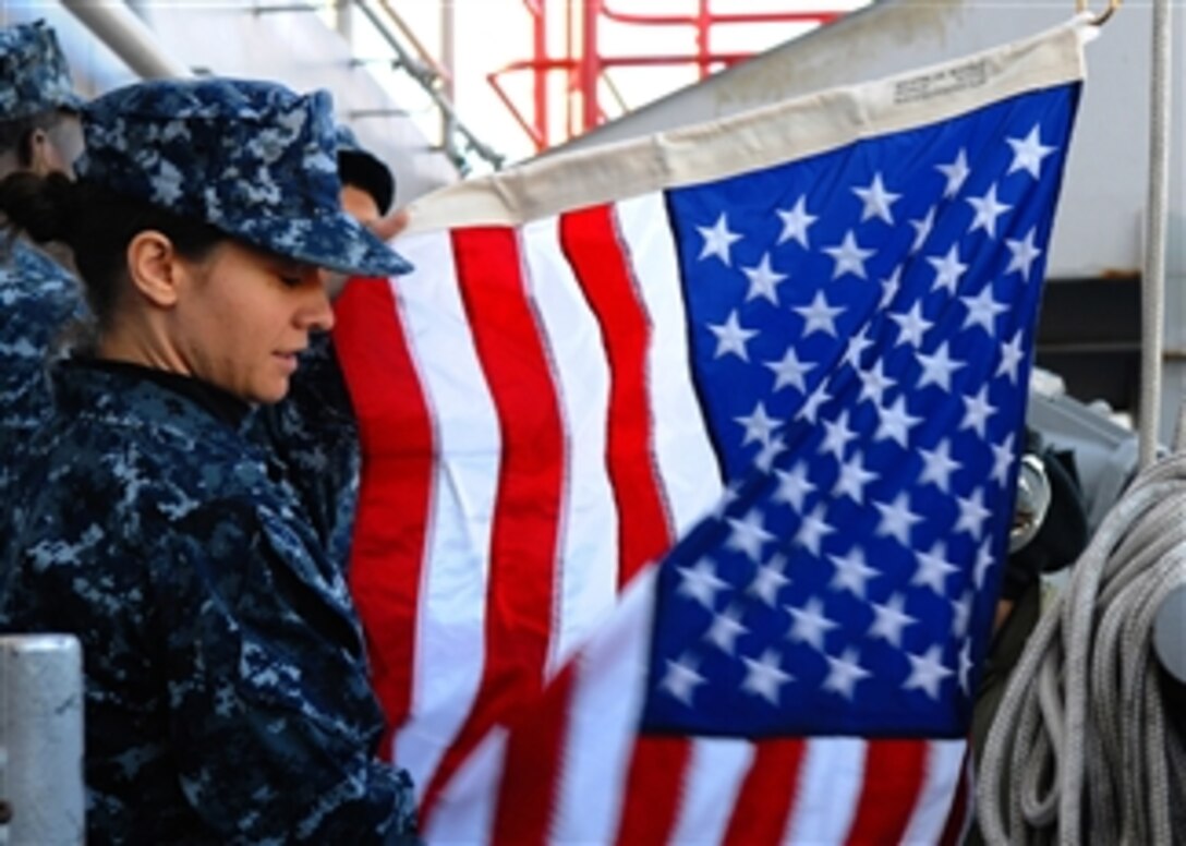 U.S. Navy Quartermaster Seaman Ingrid Devinkayne prepares a national ensign to be raised as the aircraft carrier USS Ronald Reagan (CVN 76) leaves its home port of San Diego, Calif., on Jan. 4, 2011.  The Ronald Reagan was departing to conduct operations in preparation for a deployment.  