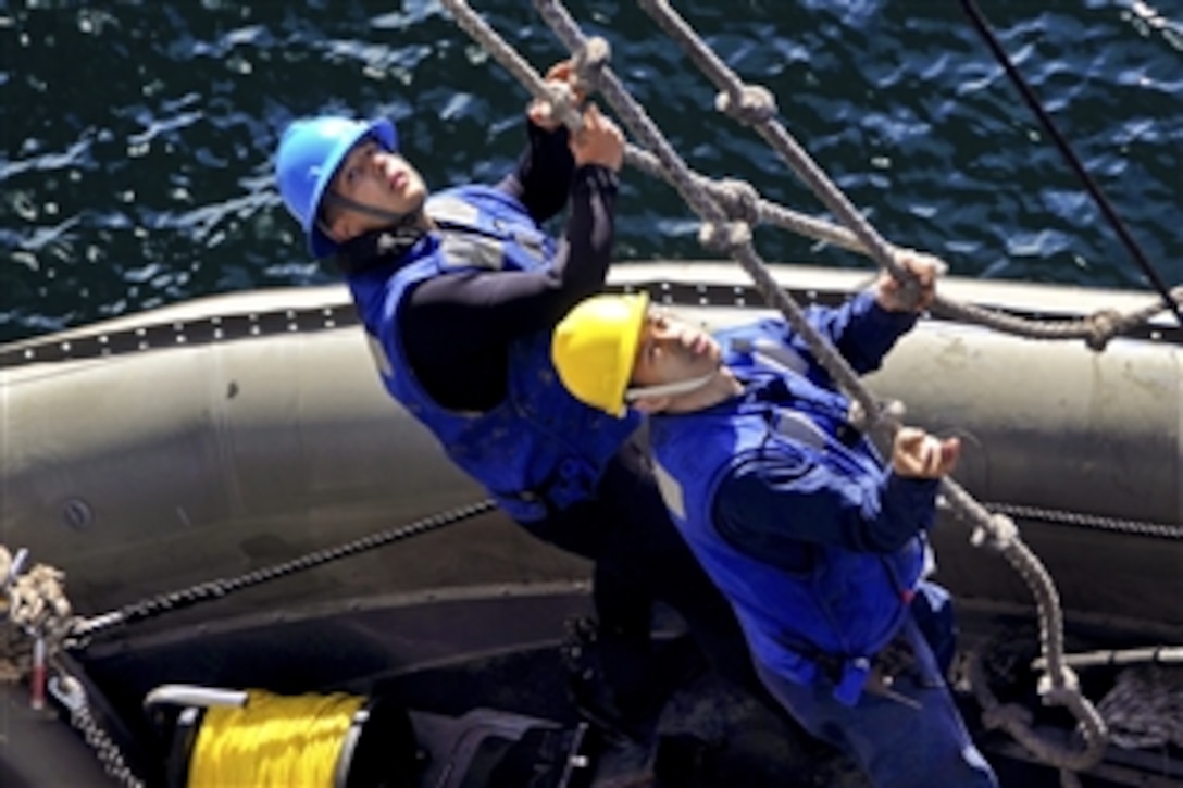 U.S. Navy Petty Officers 3rd Class Michael McClure, left, and 2nd Class Alex Luna hold lines to steady a rigid-hull inflatable boat as they are lifted onto the starboard boat deck aboard the aircraft carrier USS Ronald Reagan during an exercise in the Pacific Ocean, Jan. 5, 2011. The Ronald Reagan is underway conducting operations in preparation for an upcoming deployment.