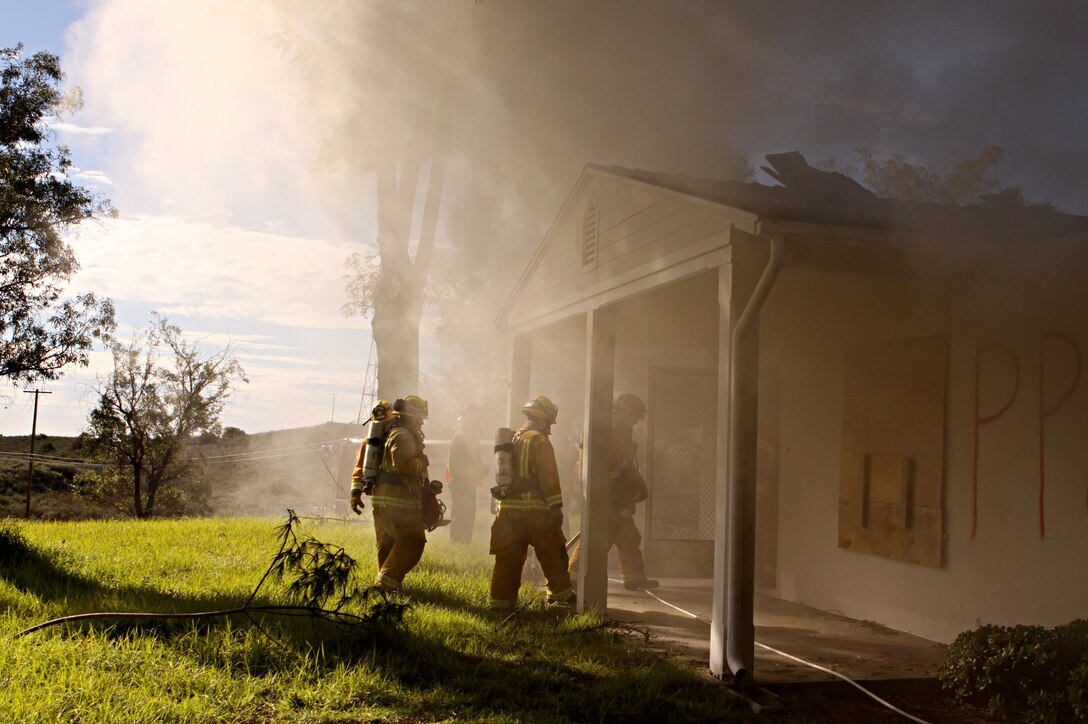 Firefighters from Camp Pendleton Fire Department and North County Area Fire Departments demonstrate their duties by blazing their way through several simulated fire scenarios in the old base housing units at Naval Weapons Station Fallbrook, Jan. 6. Since the old structures were scheduled for demolition, the U.S. Navy donated them to the fire departments to use for advanced training.