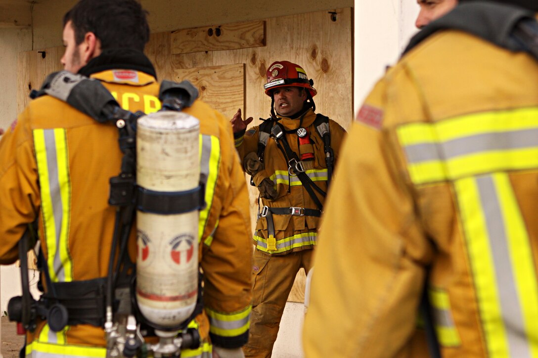 Lt. Carlos Camarena (center), Camp Pendleton Fire Department, directs firefighters from Camp Pendleton Fire Department and North County Area Fire Departments while blazing their way through several simulated fire situations in the old base housing units at Naval Weapons Station Fallbrook, Jan. 6. Since the old structures were scheduled for demolition, the U.S. Navy donated them to the fire departments to use for advanced training.