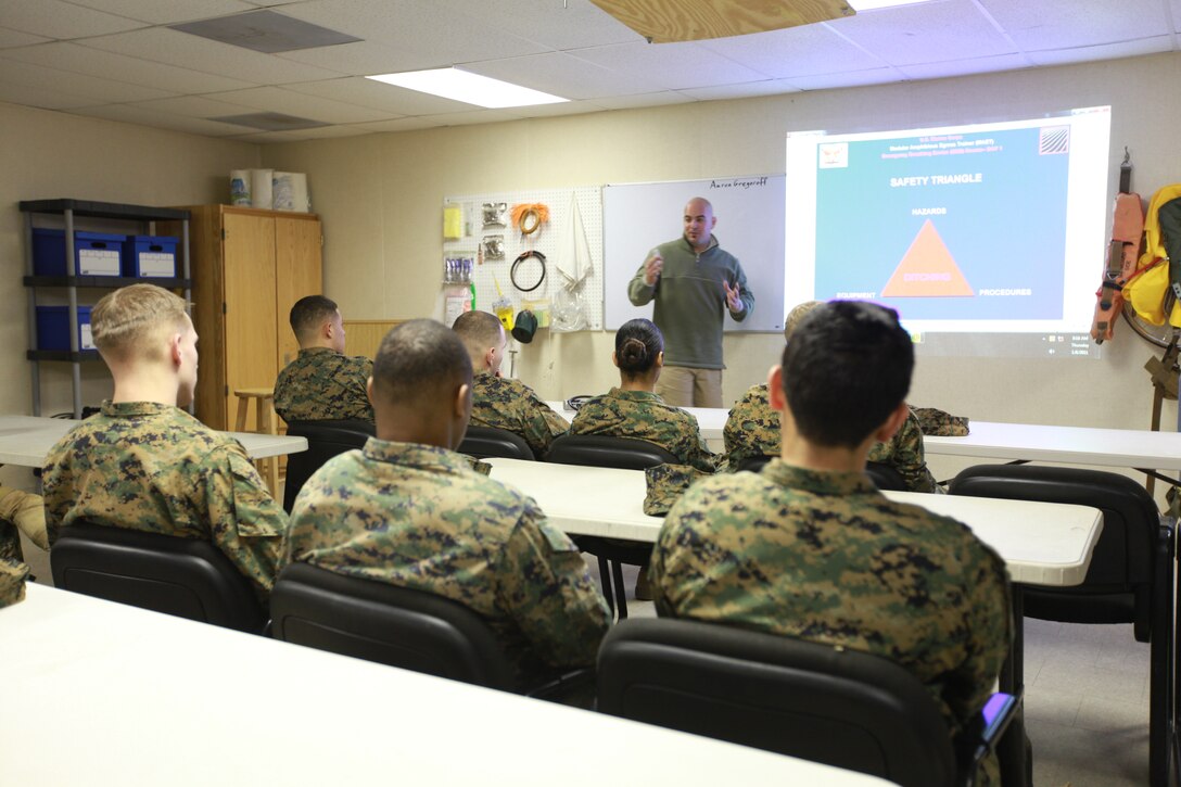 Aaron Gregoroff, lead Modular Amphibious Egress Trainer course instructor, describes a slide during a presentation to Marines with the 11th Marine Expeditionary Unit and Combat Logistics Battalion 11 as it pertains to the two-day course here Jan. 6. The course provides military personnel with the skills necessary to coordinate an egress from a sinking helicopter and survive at sea until rescued.