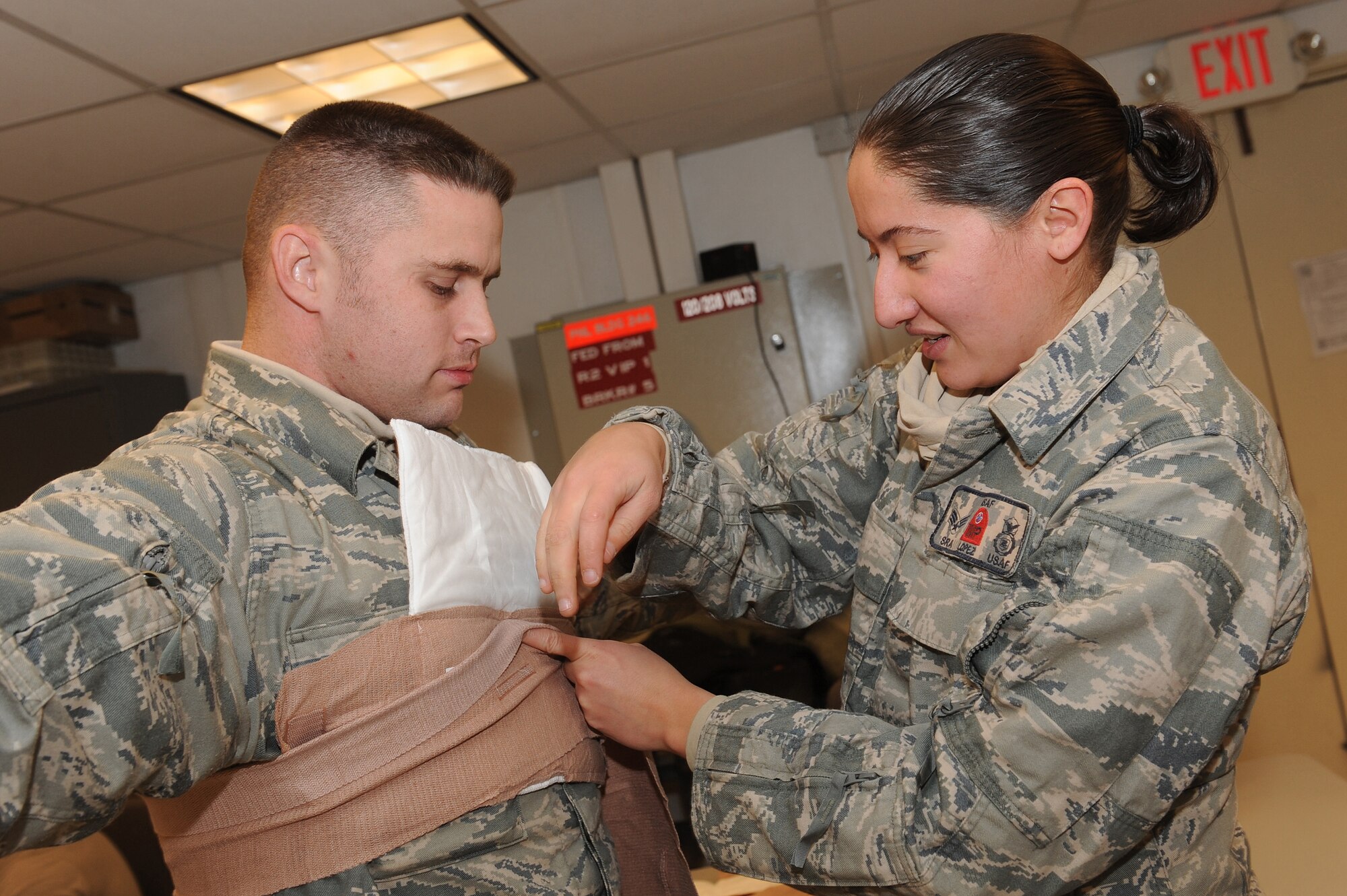 Senior Airman Janell Lopez tightens bandages to the chest of Master Sgt. Cameron Vestal during the hands-on portion of the First Responder Self-Aid and Buddy Care training Jan. 3, 2011, at Kandahar Airfield, Afghanistan. Sergeant Blitz provided refresher training to International Security Assistance Force Military Police members on combat casualty response kits that will be readily available in base patrol vehicles. Sergeant Vestal, from Dallas, is the ISAF MP flight chief, and Airman Lopez, from San Antonio, is a patrolman assigned to the ISAF MP.  (U.S. Air Force photo by Tech. Sgt. Chad Chisholm/Released)