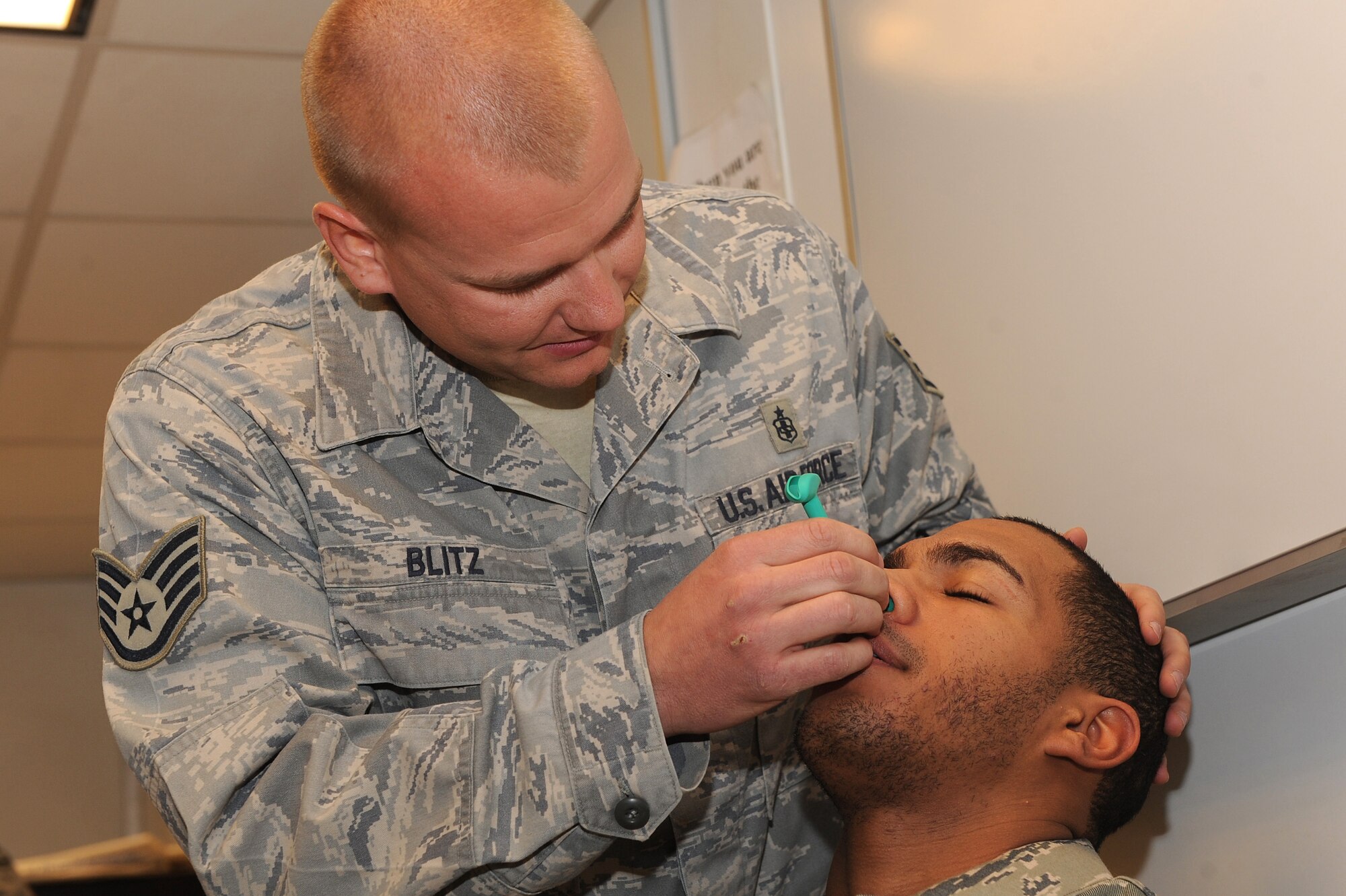 Staff Sgt. Matt Blitz demonstrates how to insert a nasal pharyngeal airway on a volunteer Jan. 3, 2011, at Kandahar Airfield, Afghanistan.  Sergeant Blitz provided refresher training to International Security Assistance Force Military Police members on combat casualty response kits that will be readily available in base patrol vehicles. Sergeant Blitz, from Spangdahlem Air Base, Germany, is an independent duty medical technician assigned to the 73rd Expeditionary Air Control Squadron. (U.S. Air Force photo by Tech. Sgt. Chad Chisholm/Released)