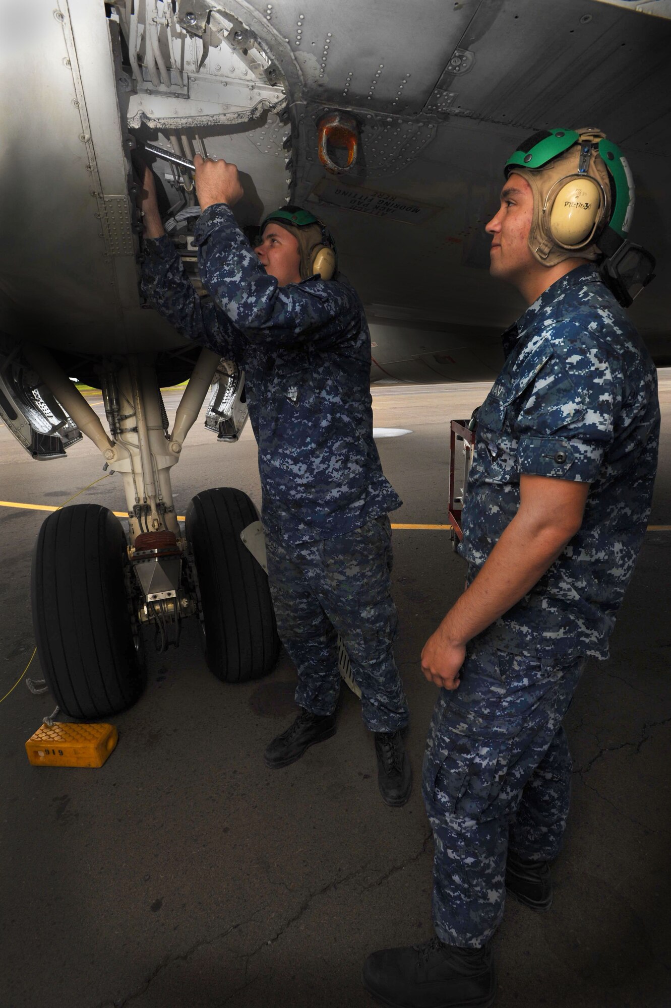 U.S. Navy Airman Joseph Hays, an aviation structural mechanic, checks the hydraulic line on the P-3 Orion as Airman Michael Dimio, also an aviatiion structural mechanic, looks on on the 15th Wing flightline Jan. 6. The aircraft are temporarily being housed by the 15th Wing due to runway construction at Marine Corps Base Hawaii. The P-3s were initially released to the Navy in 1962 and are used to detect enemy submarines and aircraft. They are also used to view battlespace in order to relay information instantaneously to ground troops. (U.S. Air Force Photo/Airman 1st Class Lauren Main)