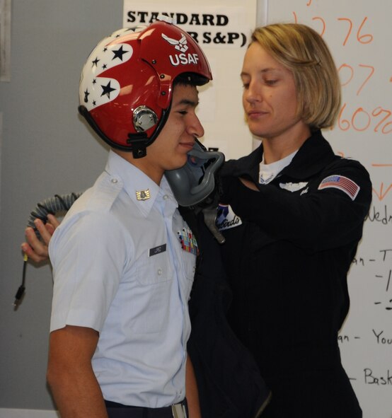 LAUGHLIN AIR FORCE BASE, Texas – Capt. Kristen Hubbard, Thunderbirds advance pilot and narrator, helps a Junior ROTC student at Del Rio High School try on her helmet Jan. 7. Captain Hubbard was here to promote the Thunderbirds’ air show at Laughlin Oct. 15 and 16. (U.S. Air Force photo by Airman 1st Class Blake Mize) 