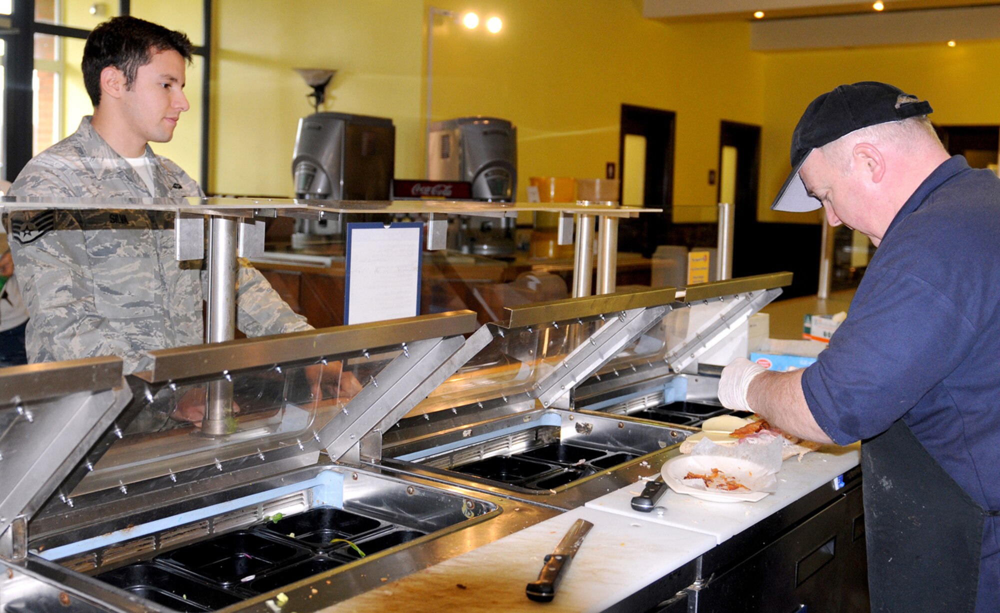 RAF MILDENHALL, England -- Staff Sgt. Brian Silva, 321st Special Tactics Squadron, waits on a sandwich made by Bob Erwin, 100th Force Support Squadron, at the Galaxy Club Jan. 7, 2011. As a result of the 2010 Quality of Life Survey, the sandwich bar at the Galaxy Club opened as part of the "Healthy and Fit for Life" campaign which includes healthy option menus at all 100th FSS eating facilities. (U.S. Air Force photo/Senior Airman Tabitha M. Lee)