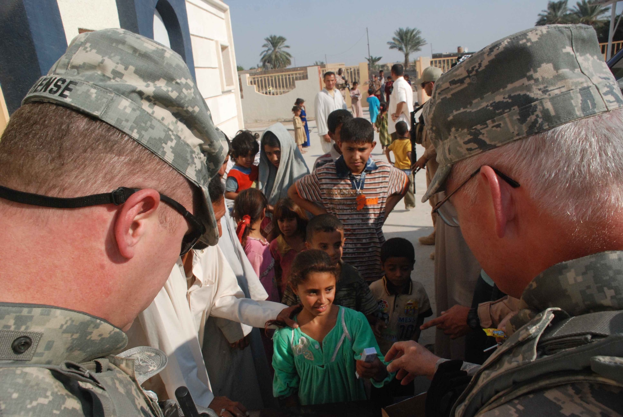 U.S. Army Maj. Kurt Hense , left, and U.S. Air Force Maj. Terry Jenson, hand out candy and school supplies to children at a school outside of Nasiriyah Iraq.