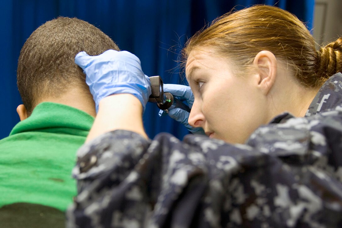 U.S. Navy Petty Officer 1st Class Tarren Windham checks a sailor's ear for an infection aboard the aircraft carrier USS Carl Vinson, which is under way in the Pacific Ocean, Jan. 7, 2011. The Carl Vinson and Carrier Air Wing 17 are deployed to the U.S. 7th Fleet area of responsibility.