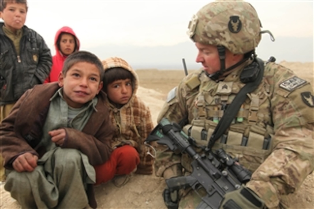U.S. Army Sgt. Adam Dean (right), a combat engineer with 2nd Platoon, 832nd Engineer Company, attached to 1st Squadron, 113th Cavalry Regiment, speaks to a couple of young Afghan boys from the village of Qalah-ye Boland in Parwan province, Afghanistan, on Dec. 30, 2010.  U.S. soldiers of 832nd Engineer Company visited the village to assess the area and to attend a key leader engagement with the Malik.  
