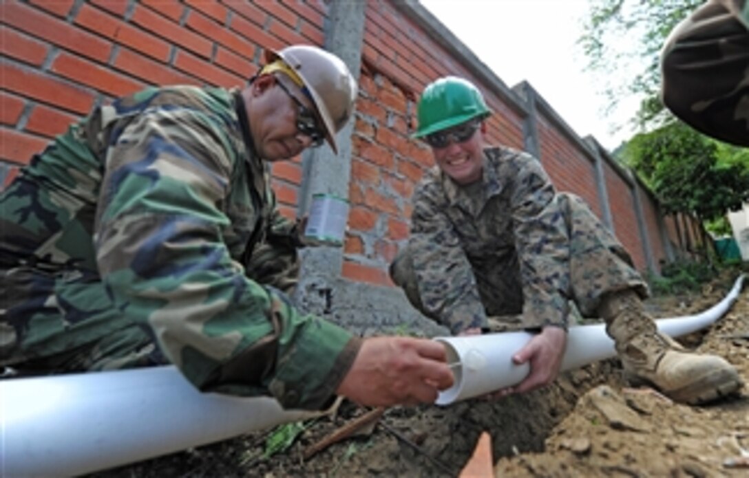 U.S. Navy Petty Officer 1st Class Carlos Sanchez (left), assigned to Naval Mobile Construction Battalion 28 Detail Bravo, applies concrete sealant to a sewage pipe while Marine Corps Lance Cpl. Stephen Mcdonaldhale, assigned to 2nd Marine Logistics Group, holds it steady at Escuela Eloy Alfaro School in Manta, Ecuador, on Jan. 5, 2011.  U.S. sailors, Marines and Ecuadorian naval infantrymen partnered at the school for week-long subject matter expert exchange during Southern Partnership Station 2011, an annual deployment of U.S. ships to the U.S. Southern Command's area of responsibility in the Caribbean and Latin America involving information sharing with navies, coast guards and civilian services throughout the region.  