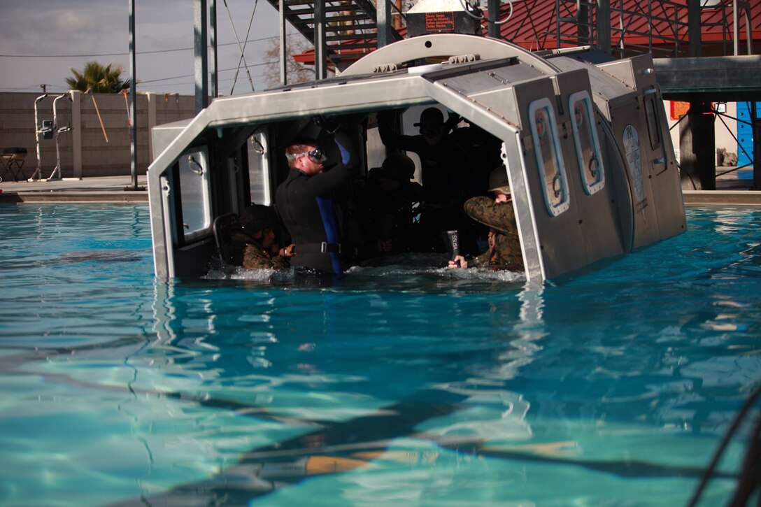 Marines with the 11th Marine Expeditionary Unit and Combat Logistics Battalion 11 are submerged to simulate escaping a CH-46 Sea Knight during a crash in water here Jan. 7. The Marines learn how to properly exit a sinking CH-46 or CH-53 Super Stallion aircraft and how to use the Intermediate Passenger Helicopter Aircrew Breathing Device, which is similar to a small scuba tank that provides up to two minutes of compressed air.
