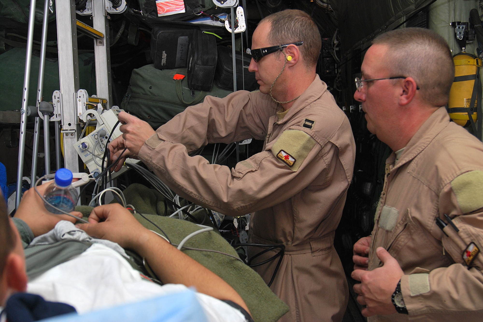 Capt. John Eggert and Master Sgt. Rich Pakula setup medical equipment for their patient inside a C-130H Hercules Jan. 5, 2011, at Kandahar Airfield, Afghanistan. The critical care air transport team is a specialized three-person team that recreates an intensive care unit environment within an aircraft during aeromedical evacuations. Assigned to the 451st Expeditionary Aeromedical Evacuation Squadron CCATT, Captain Eggert is a nurse and Sergeant Pakula is a respiratory technician. (U.S. Air Force photo by Senior Airman Melissa B. White/Released)