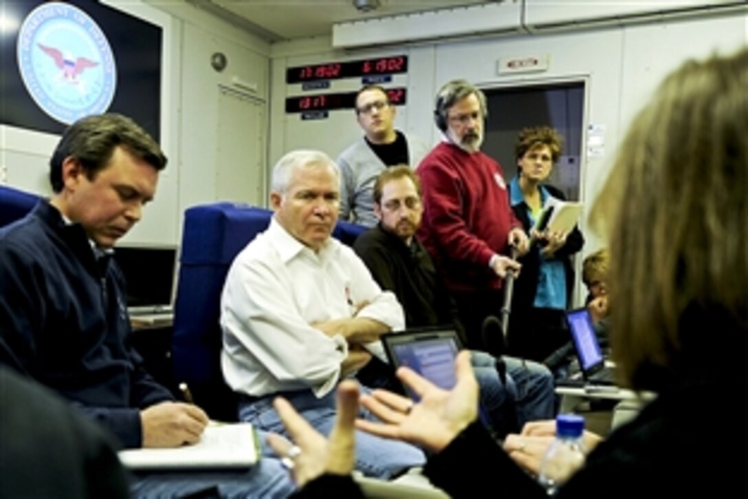 U.S. Defense Secretary Robert M. Gates and members of his staff listen to a reporter's question during a press availability on board the National Airborne Operations Center aircraft on Andrews Air Force Base, Md., Jan 8, 2011. Gates departed on a seven-day trip to Asia to discuss defense issues. 