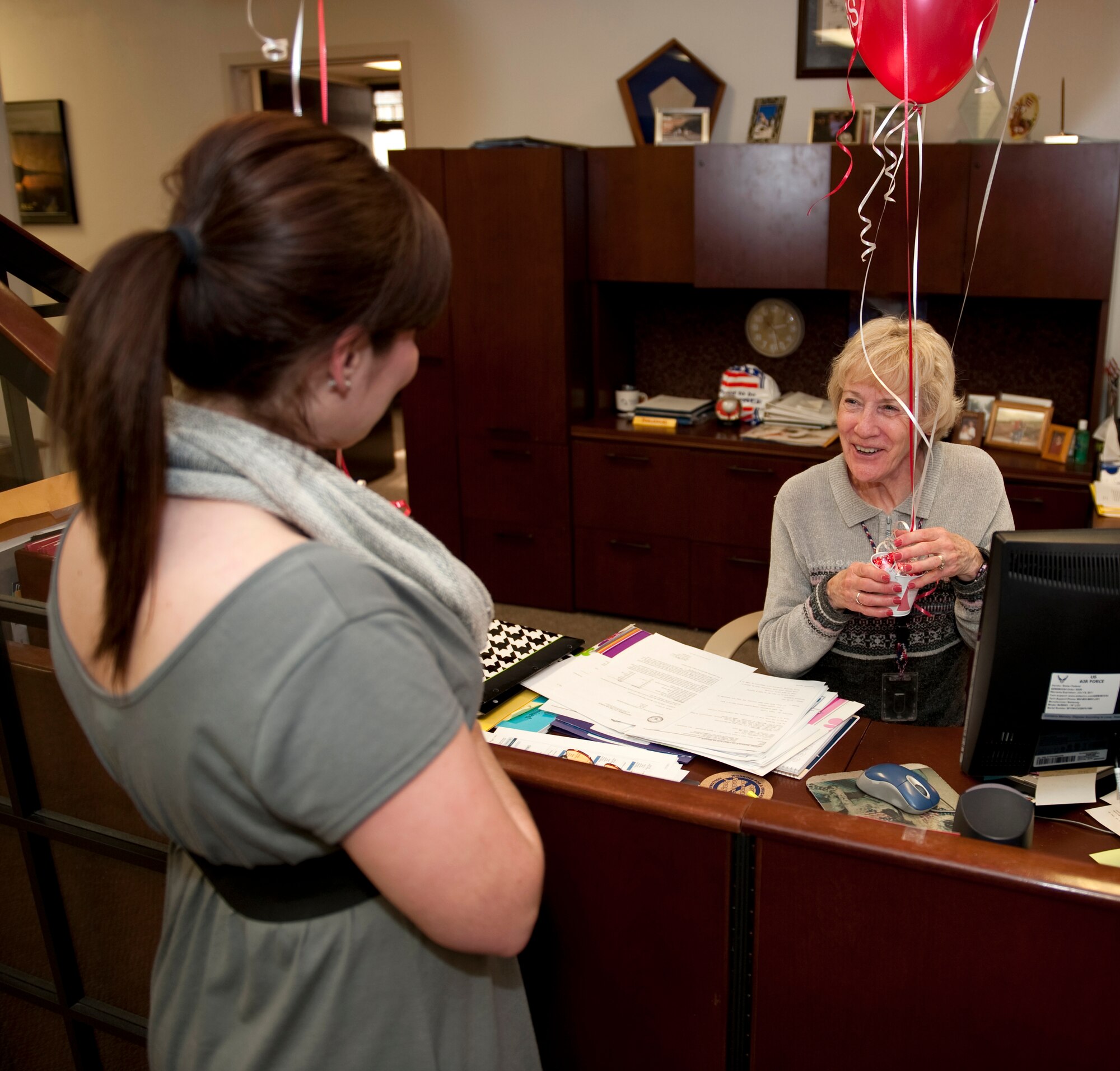 HOLLOMAN AIR FORCE BASE, N.M. -- Barbara Hensley, 49th Wing commander's secretary, thanks Amanda Gallagher, 49th Force Support Squadron Marketing director, for the unsuspected delivery of a balloon bouquet Jan. 10, 2011. Members of the 49th FSS Marketing Office hand delivered balloon bouquets anchored with Hershey Kisses to six unsuspecting members Jan. 10, and plan to deliver around 34 more in a week-long "Kissed by FSS" event. The bouquets are custom-made by the Community Activity Center's Balloon Box and during the course of the event, which ends Jan. 14, balloon bouquet orders are 10 percent off. (U.S. Air Force photo by Senior Airman Michael Means/Released)
