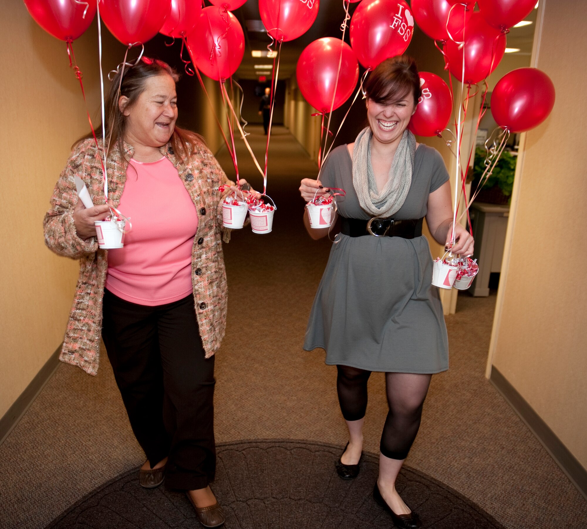 HOLLOMAN AIR FORCE BASE, N.M. -- Amanda Gallagher and Gloria Sanborn, both with the 49th Force Support Squadron, walk down the hallway of the 49th Wing Headquarters building during the "Kissed by FSS" event Jan. 10, 2011.They delivered balloon bouquets anchored with Hershey Kisses to six unsuspecting members and plan to deliver around 34 more during the course of the week. The 49th FSS Marketing Office is delivering the bouquets -- custom-made by the Community Activity Center's Balloon Box -- to show appreciation to Team Holloman members, while also kicking off the Valentine's Day season. (U.S. Air Force photo by Senior Airman Michael Means/Released)