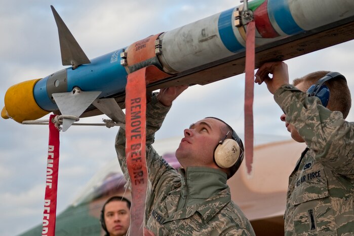NELLIS AIR FORCE BASE, Nev. -- Senior Airman Benjamin Whitfield, and Airman 1st Class Karl Nielson, 57th Aircraft Maintenance Squadron aircraft armament systems weapons load team members,  secure a AIM-9 air to air missile on a F-16 Fighting Falcon during a weapons load competition on the Nellis flightline Jan. 7. Weapons load competitions are conducted quarterly to keep Airmen sharp and recognize superior performers. Weapons load teams are evaluated for their use of the checklist, safety, and overall speed. (U.S. Air Force photo by Airman 1st Class George Goslin)
