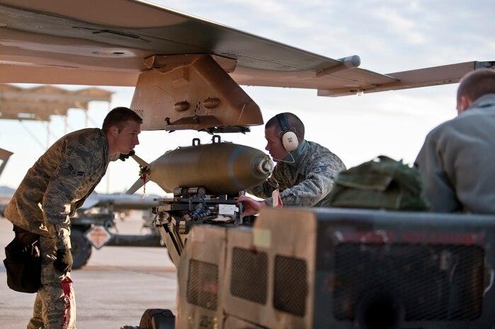 NELLIS AIR FORCE BASE, Nev. -- Senior Airman Benjamin Whitfield, Airman 1st Class Karl Nielson, and Airman 1st Class Trevor Watts 57th Aircraft Maintenance Squadron aircraft armament systems weapons load team members, use a MJ-1 Jammer to load a MK-82 bomb on a F-16 Fighting Falcon during a weapons load competition on the Nellis flightline Jan. 7. Weapons load competitions are conducted quarterly to keep Airmen sharp and recognize superior performers. Weapons load teams are evaluated for their use of the checklist, safety, and overall speed. (U.S. Air Force photo by Airman 1st Class George Goslin)
