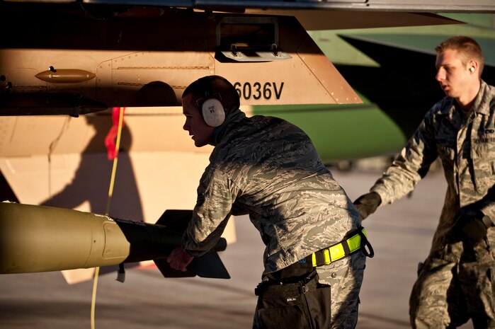 NELLIS AIR FORCE BASE, Nev. -- Senior Airman Benjamin Whitfield, and Airman 1st Class Karl Nielson, 57th Aircraft Maintenance Squadron aircraft armament systems weapons load team members, use a MJ-1 Jammer to position a MK-82 bomb on a F-16 Fighting Falcon during a weapons load competition on the Nellis flightline Jan. 7. Weapons load competitions are conducted quarterly to keep Airmen sharp and recognize superior performers. Weapons load teams are evaluated for their use of the checklist, safety, and overall speed. (U.S. Air Force photo by Airman 1st Class George Goslin)
