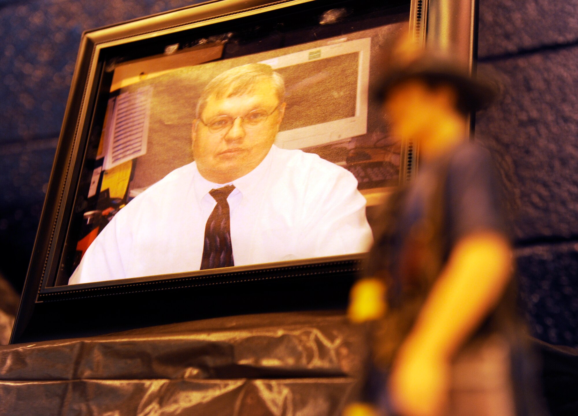 A photo of Rick Grammer, Air Mobility Command fire chief, is displayed at a Final Alarm Ceremony, Jan. 10, 2010 at Scott Air Force Base, Ill. Mr. Grammer passed away last week. A Final Alarm Ceremony is a traditional final tribute to a firefighter who has passed.  The ceremony begins by calling the passed firefighter’s name and is followed by the ringing of the ceremonial fire bell.  Bagpipes are also commonly played.  The ceremony represents the firefighter’s final call to duty. (U.S. Air Force photo/ Staff Sgt. Ryan Crane)
