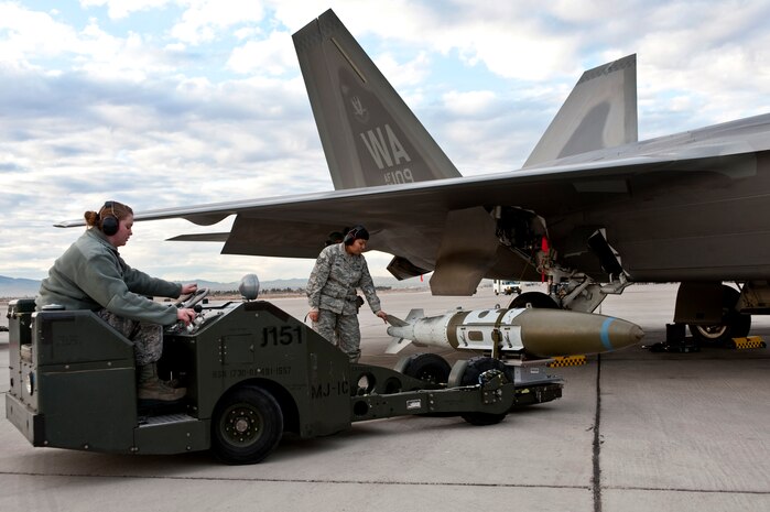 NELLIS AIR FORCE BASE, Nev. -- Airman 1st Class Ashley Hill and Staff Sgt. Ragina James, 57th Aircraft Maintenance Squadron aircraft armament systems weapons load team members, use a MJ-1 Jammer to load a MK-84 2000-pound bomb on a F-22 Raptor during a weapons load competition on the Nellis flightline Jan. 7. Weapons load competitions are conducted quarterly to keep Airmen sharp and recognize superior performers. Weapons load teams are evaluated for their use of the checklist, safety, and overall speed. (U.S. Air Force photo by Tech Sgt. Michael R. Holzworth)


