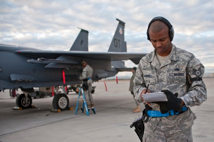 NELLIS AIR FORCE BASE, Nev. -- Staff Sgt. Melvin Marshall, 757th Aircraft Maintenance Squadron aircraft armament systems craftsman, reviews his checklist while Senior Airman Carlyle Douglas 757th Aircraft Maintenance Squadron aircraft armament systems apprentice, prepares a F-15 Eagle for a weapons load during a weapons load competition on the Nellis flightline Jan. 7. Weapons load competitions are conducted quarterly to keep Airmen sharp and recognize superior performers. Weapons load teams are evaluated for their use of the checklist, safety, and overall speed. (U.S. Air Force photo by Tech Sgt. Michael R. Holzworth)


