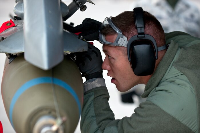NELLIS AIR FORCE BASE, Nev. --  Airman 1st Class Lucas Wolf, 57th Aircraft Maintenance Squadron aircraft armament systems apprentice, secures a MK-82 bomb on a F-16 Fighting Falcon during a weapons load competition on the Nellis flightline Jan. 7. Weapons load competitions are conducted quarterly to keep Airmen sharp and recognize superior performers. Weapons load teams are evaluated for their use of the checklist, safety, and overall speed. (U.S. Air Force photo by Tech Sgt. Michael R. Holzworth)