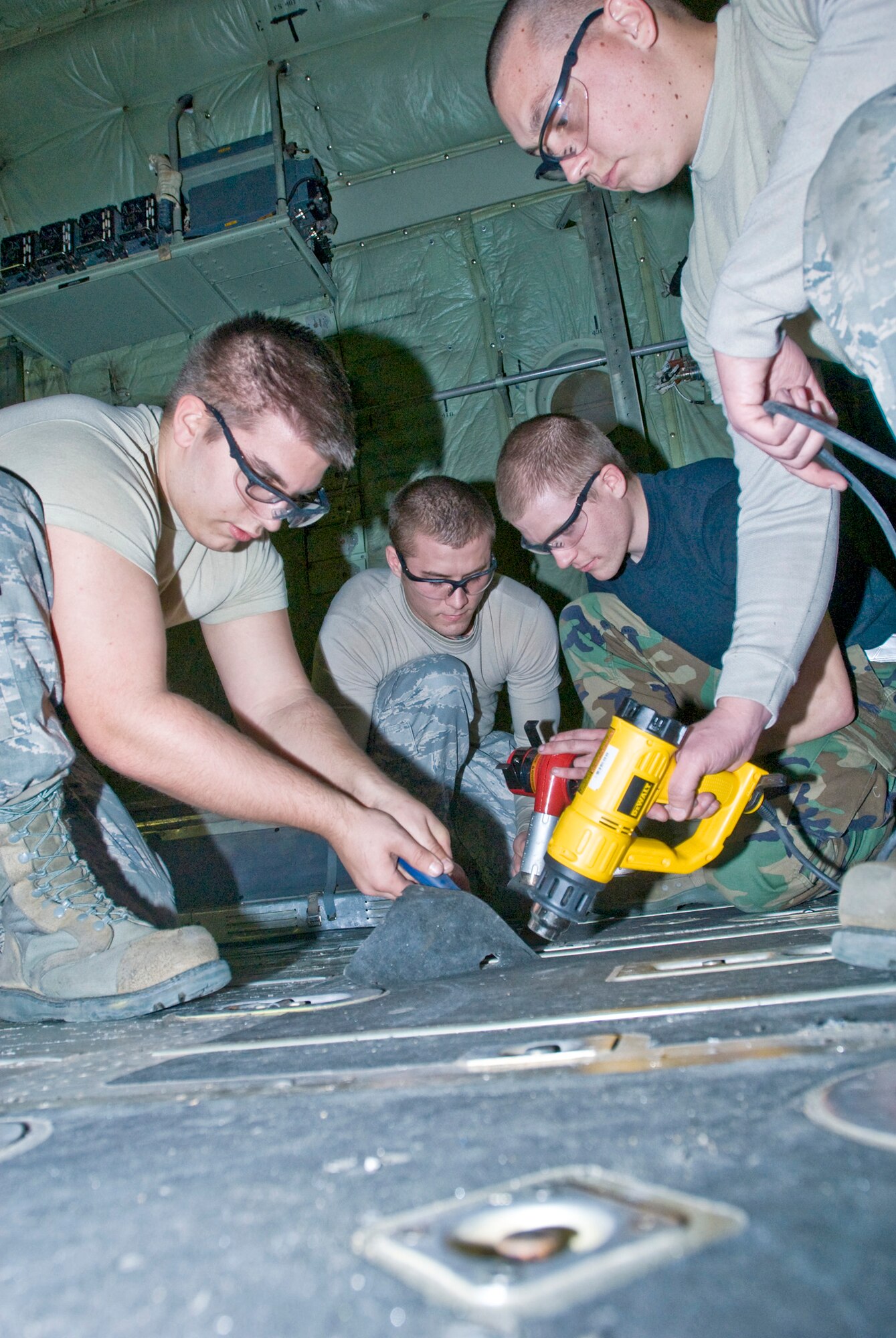 (From left) Airman 1st Class David Lee, Senior Airmen Eric McGarrh and Jason Heathington and Airman 1st Class Evan Owens work together to remove anti-skid tape from a C-130 Hercules? cargo floors Jan. 4, 2011, at Little Rock Air Force Base, Ark. The Air Force saves thousands of dollars by sending aircraft to be refurbished rather than sending them to depot. The Airmen are all 19th Equipment Maintenance Squadron members. (U.S. Air Force Photo/Staff Sgt. Nestor Cruz)