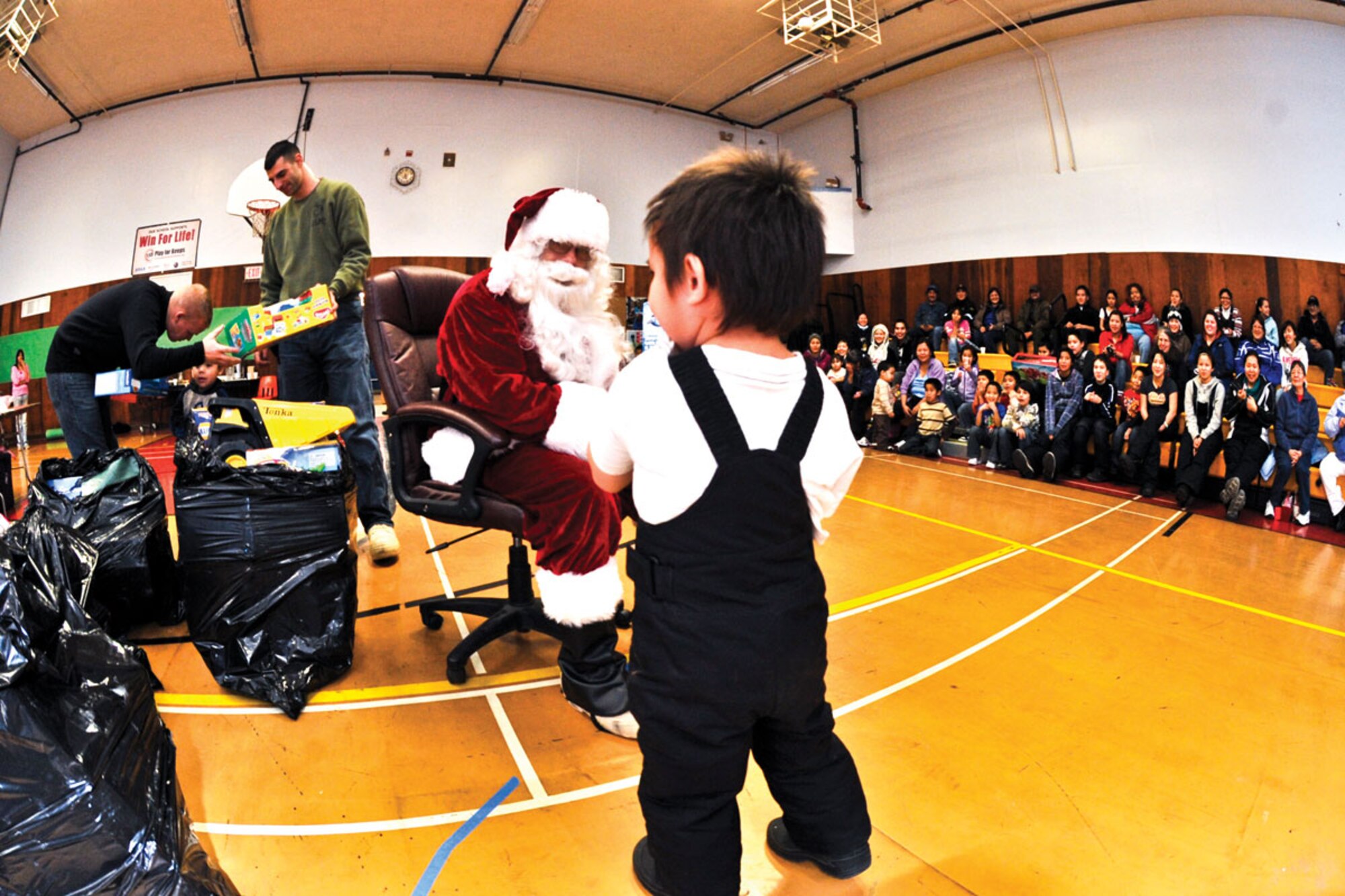 A child collects his toy from Santa as Marines begin to get the rest of the toys ready for the rest of the children. Marines from Delta Comany, Anti-terrorism Battalion, 4th Marine Division spend every December delivering toys to children in rural areas of Alaska.