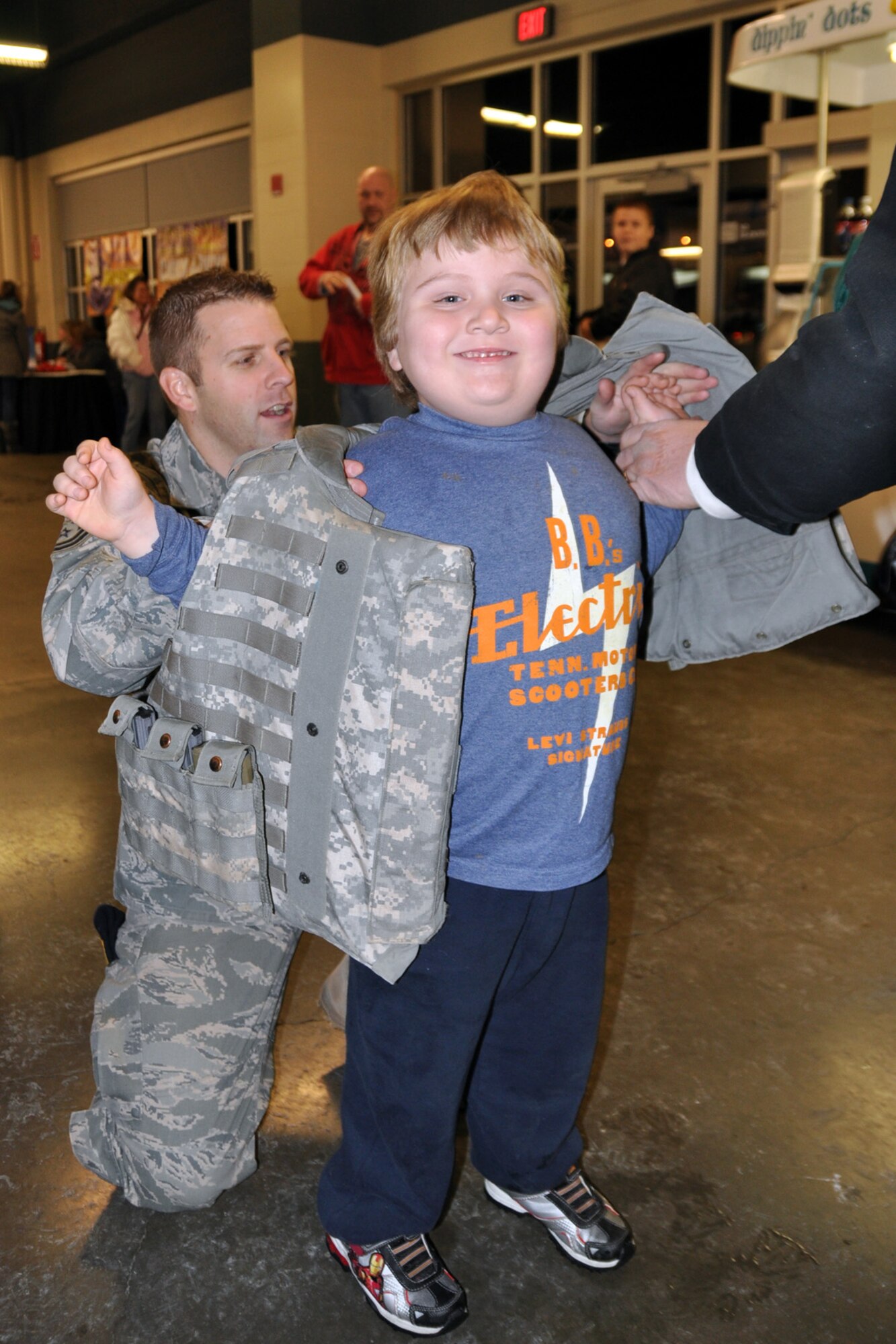YOUNGSTOWN, Ohio -- Air Force Reserve Tech. Sgt. James Bader, a fire team leader with the 910th Security Force Squadron, assists a young fan putting on a body armor vest during pre-game festivities for a Youngstown Phantoms hockey game at the Covelli Centre here, Jan. 8. Sergeant Bader and more than 130 Citizen Airmen based at nearby Youngstown Air Reserve Station, Ohio participated in Military Appreciation night activities before and during the game including a concourse display of equipment used by the 910th SFS. The Phantoms, a member of the United States Hockey League, defeated the Muskegon Lumberjacks 4-3 in front of a crowd of more than 1600 people. U.S. Air Force photo by Master Sgt. Bob Barko Jr.