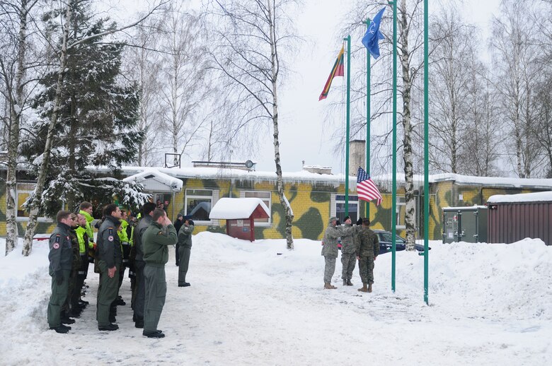 A flag detail of two Airmen and a Marine lower an American flag so a German flag can be raised during a ceremony, Jan. 5, 2011, at Lithuania Air Force Base. The flag ceremony symbolized the 493rd Expeditionary Fighter Squadron relinquishing the Baltic air policing mission to the German air force. (U.S. Air Force photo/Staff Sgt. Stephen Linch)
