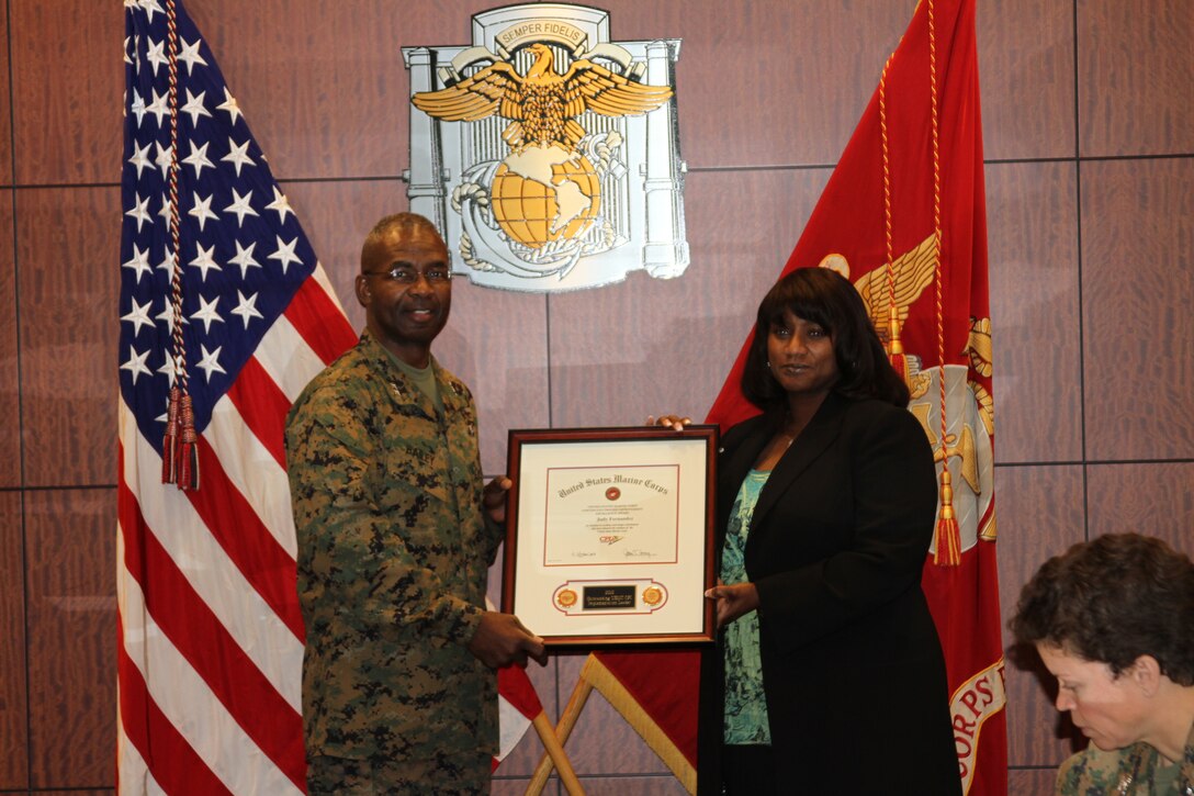 Judy Fernandez, business process office director and continuous process improvement implementation director accepts the Outstanding CPI Implementation Achievement Award presented by Maj. Gen Ronald L. Bailey, commanding general Marine Corps Recruit Depot San Diego and the Western Recruiting Region, at Marine Corps Recruit Depot San Diego, Jan. 10. Fernandez was recognized for being the top CPI implementation leader.