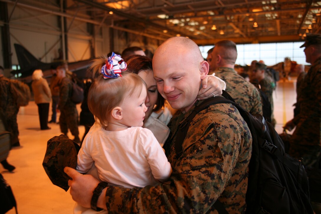 Lance Cpl. Steven Smiley hugs his wife, Katie, and daughter, Elyse, during the Marine Attack Squadron 542 homecoming in the VMA-542 hangar, Jan. 11. Smiley and more than 100 Marines returned from a six-month deployment to Marine Corps Air Station Iwakuni, Japan. “All I could think of coming off that bus was in just a few moments I’ll be holding my world in my arms once again,” said Smiley.
