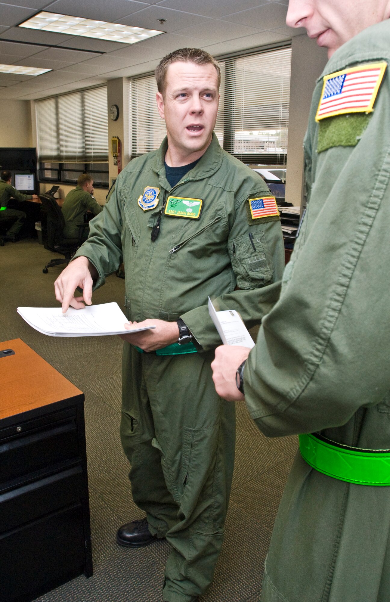 Staff Sgt. Jason Bobo, a 61st Airlift Squadron instructor flight engineer, reviews a lesson plan with a fellow instructor Dec. 14, 2010, at Little Rock Air Force Base, Ark. The Brandon, Miss., native organized “Dads on Duty” with Ward Elementary School to provide volunteers for crossing guard duty, hallway security and mentorship sessions. (U.S. Air Force photo by Staff Sgt. Nestor Cruz)