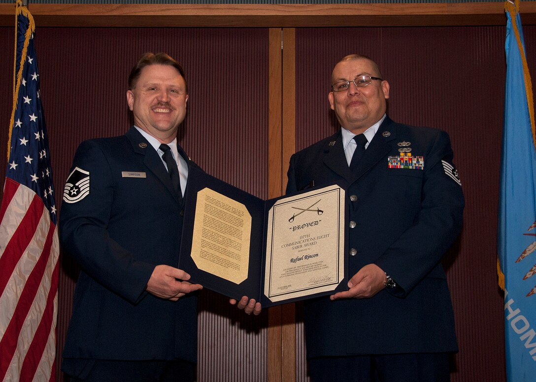 Master Sgt Edwin Simpson presents Technical Sgt Rafael Rincon, both members of 137th Communications Flight, with the Saber Award at an awards ceremony held Sunday, January 9, 2011, at Will Rogers Air National Guard Base, Okla.  The Saber Award is a Communications Flight award that ecognizes exemplary performance and work ethic.  (USAF photo by Master Sgt Roberta Thompson)