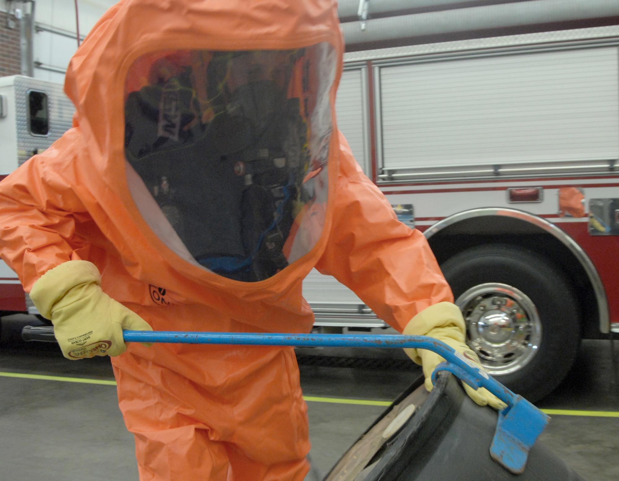 Justin Kammer uses a drum tool to lift a 55-gallon drum during a demonstration Jan. 10, 2011. He is wearing a new "ONE Suit Pro," which replaces the Hazardous Materials Level-A and Chemical, Biological, Radiological and Nuclear suits used by first responders at Goodfellow  Air Force Base, Texas, to enter immediate-danger-to-life and health-contaminated or toxic environments. The new suits are cheaper, lighter, better quality and have a longer shelf-life. Mr. Kammer is with the 17th Civil Engineer Squadron. (U.S. Air Force photo/Airman 1st Class Anne Gathua)