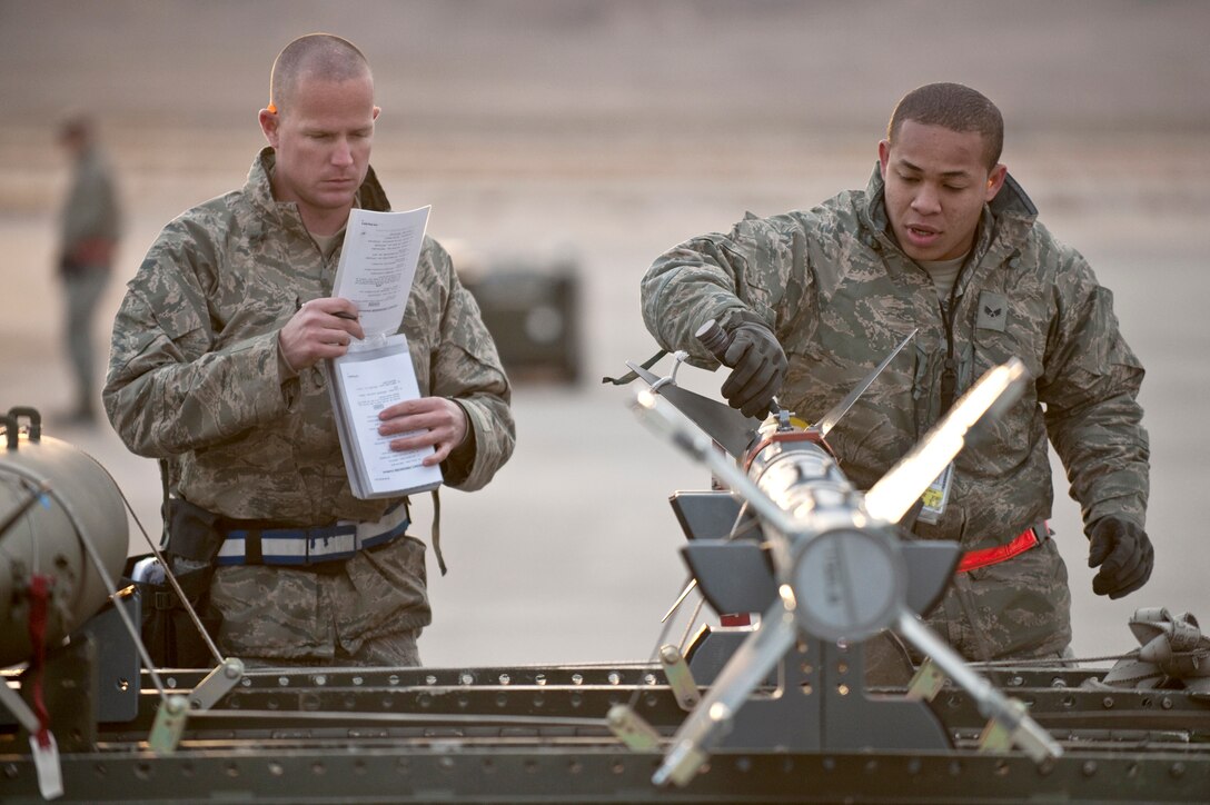 Senior Airman Eric Arrington and Senior Airman Keli Manglona go over a pre-load checklist on an AIM-9 air-to-air missile during a weapons load competition Jan. 7, 2011, at Nellis Air Force Base, Nev. Weapons load competitions are conducted quarterly to keep Airmen sharp and recognize superior performers. Weapons load teams are evaluated for their use of the checklist, safety and overall speed. Both Airmen are assigned to the 57th Aircraft Maintenance Squadron as aircraft armament systems journeymen. (U.S. Air Force photo/Tech Sgt. Michael R. Holzworth)