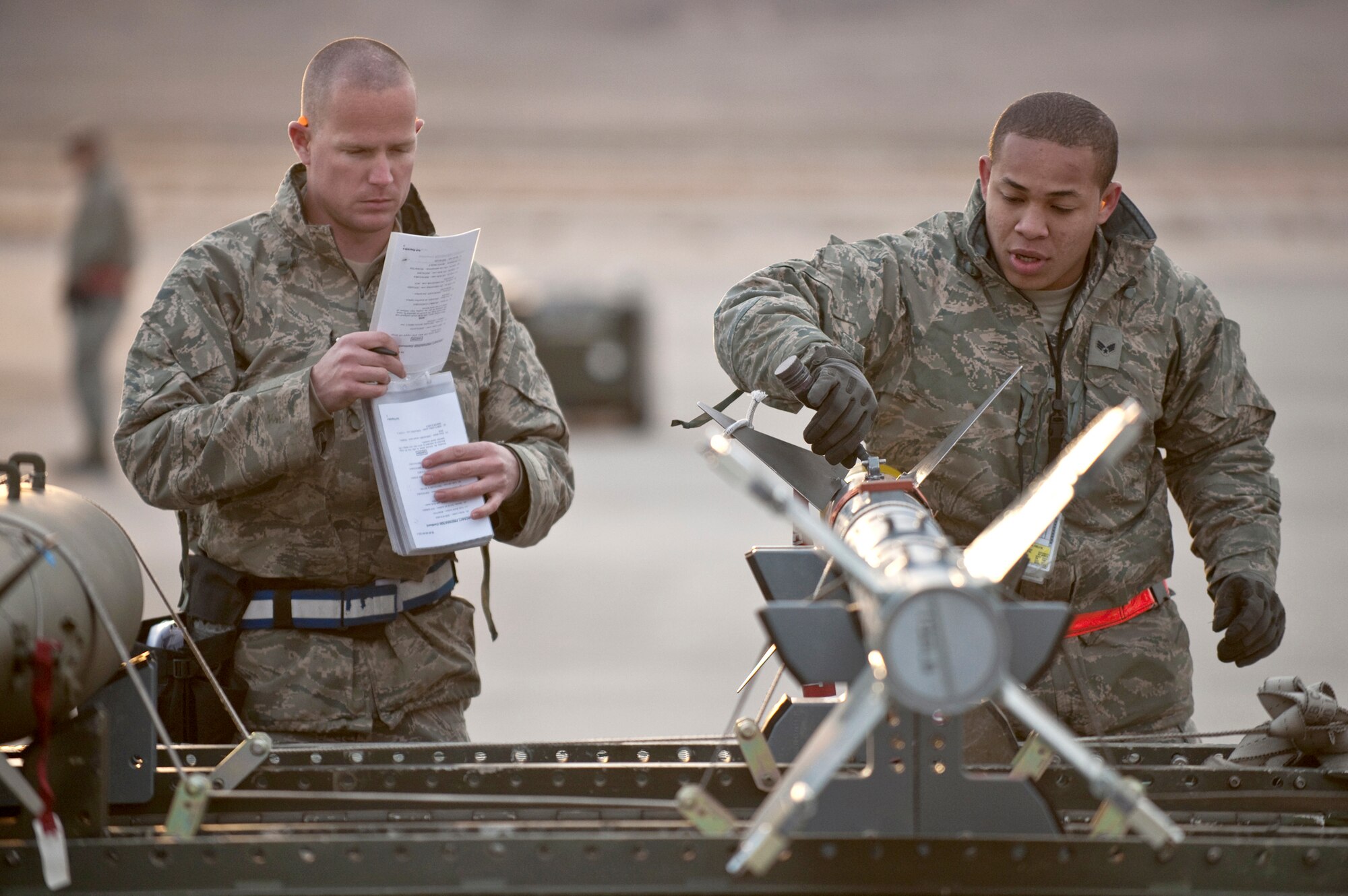 Senior Airman Eric Arrington and Senior Airman Keli Manglona go over a pre-load checklist on an AIM-9 air-to-air missile during a weapons load competition Jan. 7, 2011, at Nellis Air Force Base, Nev. Weapons load competitions are conducted quarterly to keep Airmen sharp and recognize superior performers. Weapons load teams are evaluated for their use of the checklist, safety and overall speed. Both Airmen are assigned to the 57th Aircraft Maintenance Squadron as aircraft armament systems journeymen. (U.S. Air Force photo/Tech Sgt. Michael R. Holzworth)