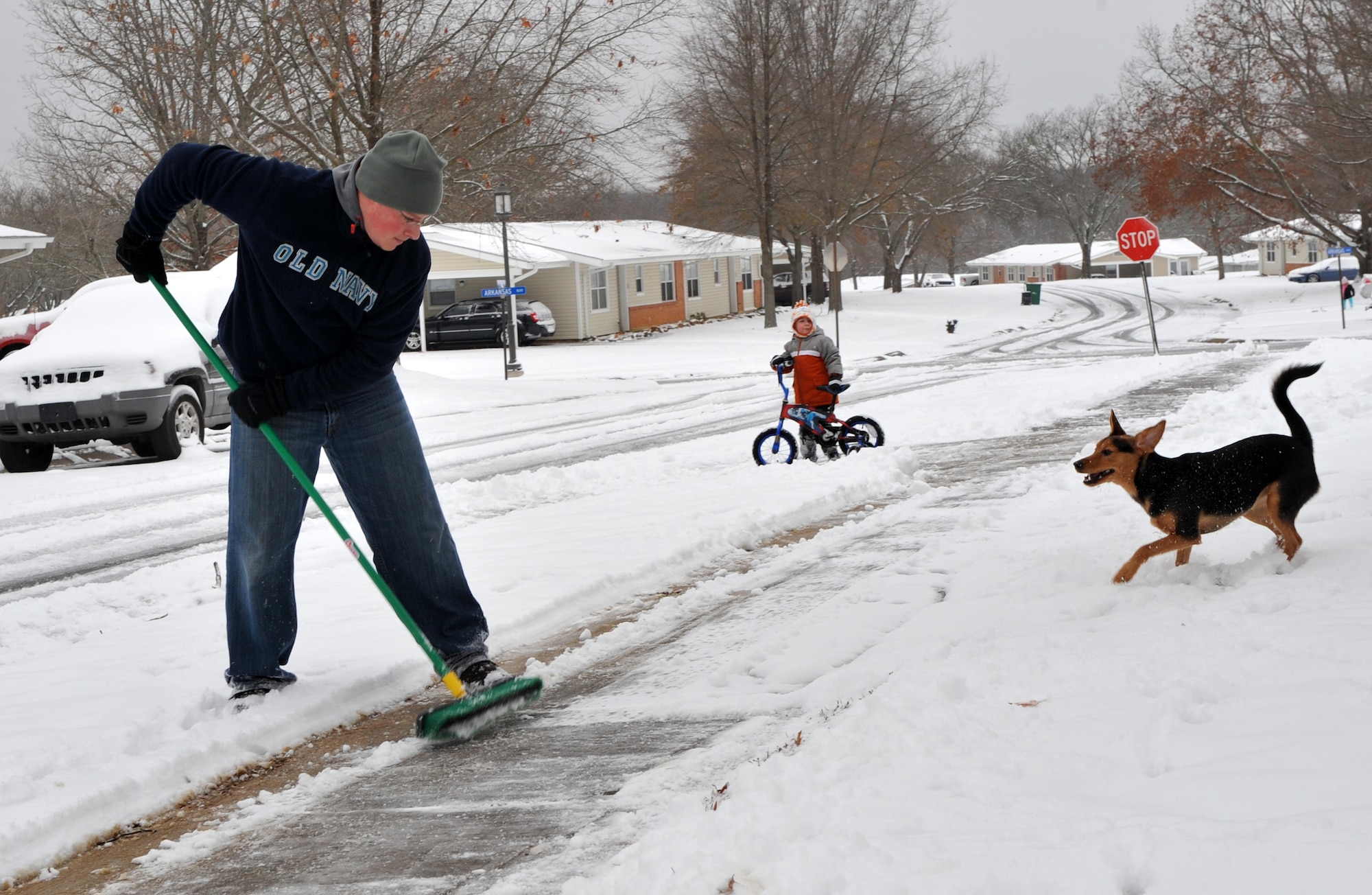 Staff Sgt. Adam Kidney, 19th Aircraft Maintenance Squadron unit deployment manager, shovels snow from the sidewalk of his house, while his son, Eli, 4, and their dog, Reese, play in the snow Jan. 10, 2011, at Little Rock Air Force Base, Ark. The first winter storm of 2011 brought up to two inches of snow. (U.S. Air Force photo by Senior Airman Gul Crockett)