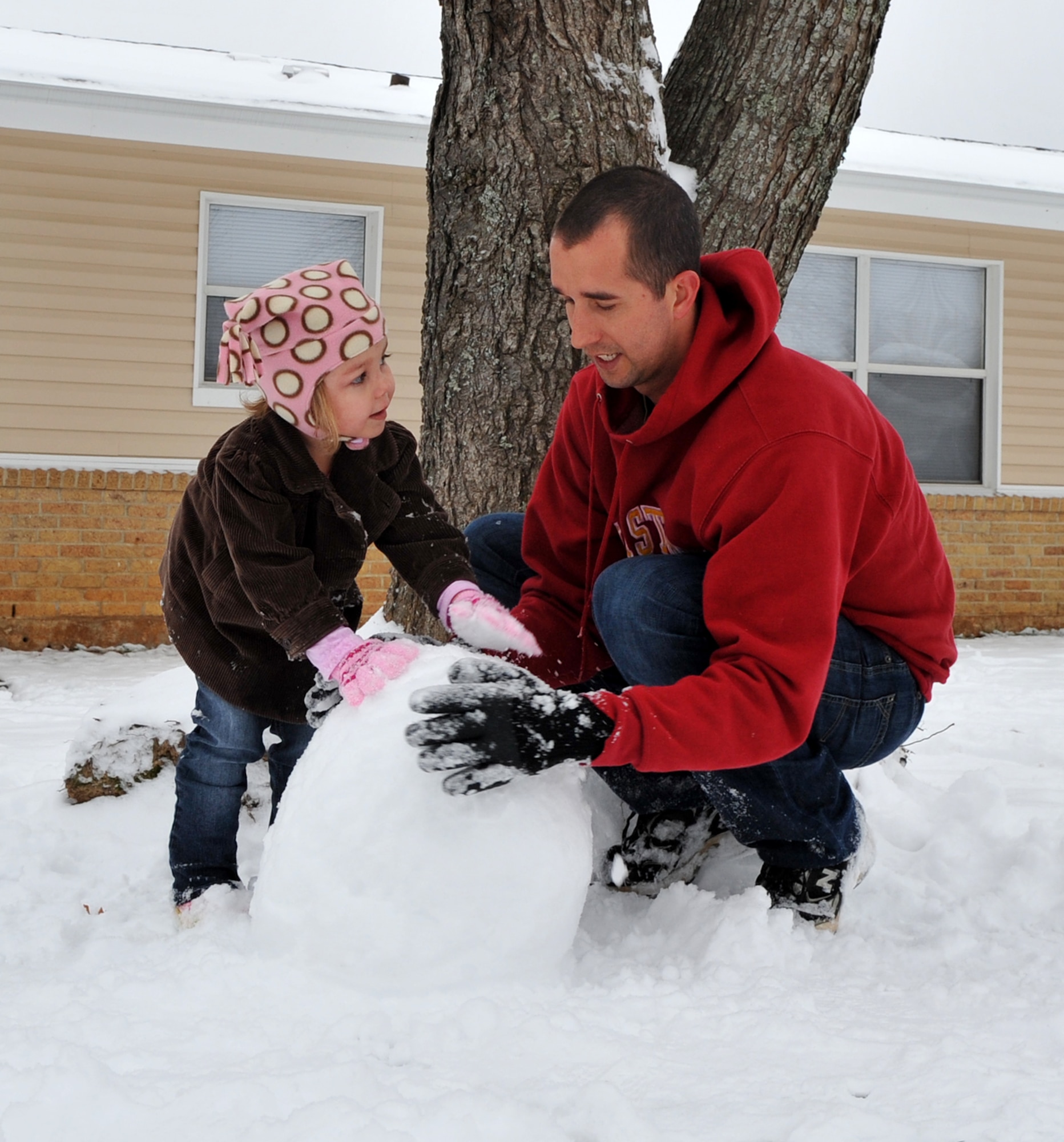 Staff Sgt. Nicholas Happel, 19th Logistics Readiness Squadron air transportation specialist, and his daughter, Lola, 4, build a snowman in front of their home Jan. 10, 2011, at Little Rock Air Force Base, Ark. The first winter storm of 2011 brought up to two inches of snow. (U.S. Air Force photo by Senior Airman Gul Crockett)
