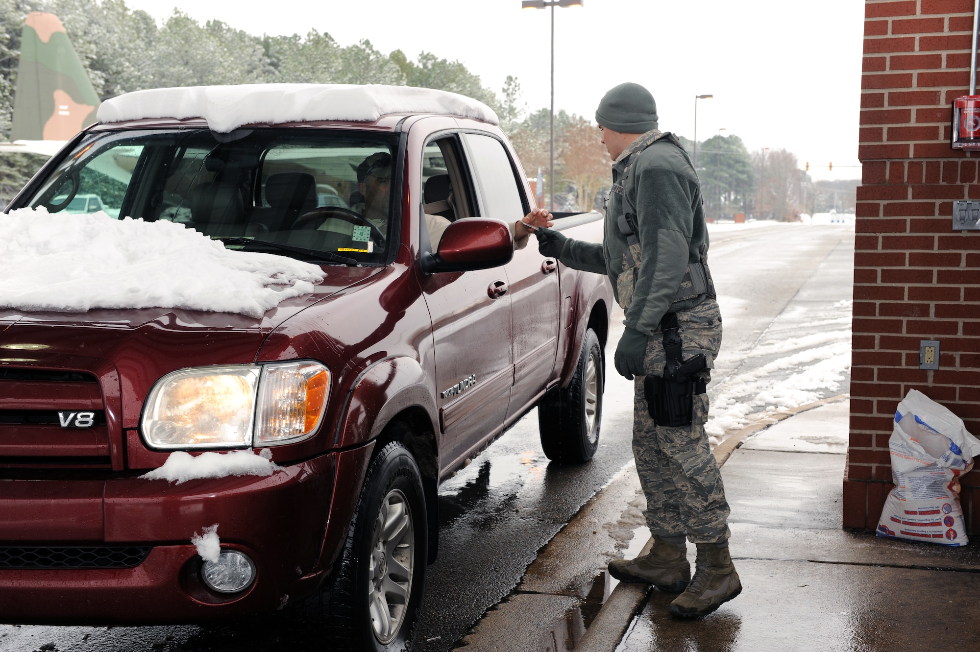 Airman Benjamin Moss, 19th Security Forces Squadron, checks ID cards at the front gate Jan. 10, 2011, at Little Rock Air Force Base, Ark. Airman Moss, along with other members of security forces, worked their required 12 hour shifts while most of the base got a snow day off. (Air Force photo by Airman 1st Class Ellora Stewart)