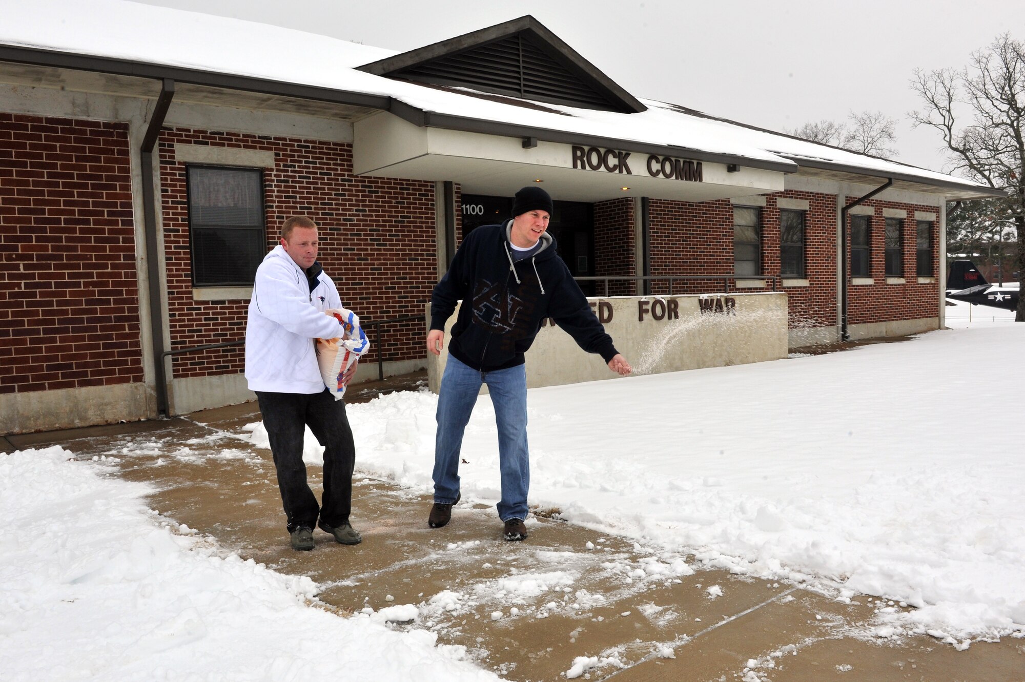 Staff Sgt. James Odom and Senior Airman Shawn Sullivan, 19th Communications Squadron com focal point technicians, spread sand and salt across the front entrance to their facility Jan. 11, 2011. Several Airmen had to clear the sidewalks and roads due to the two-inch snow storm, the first of the new year. (U.S. Air Force photo by Staff Sgt. Chris Willis)