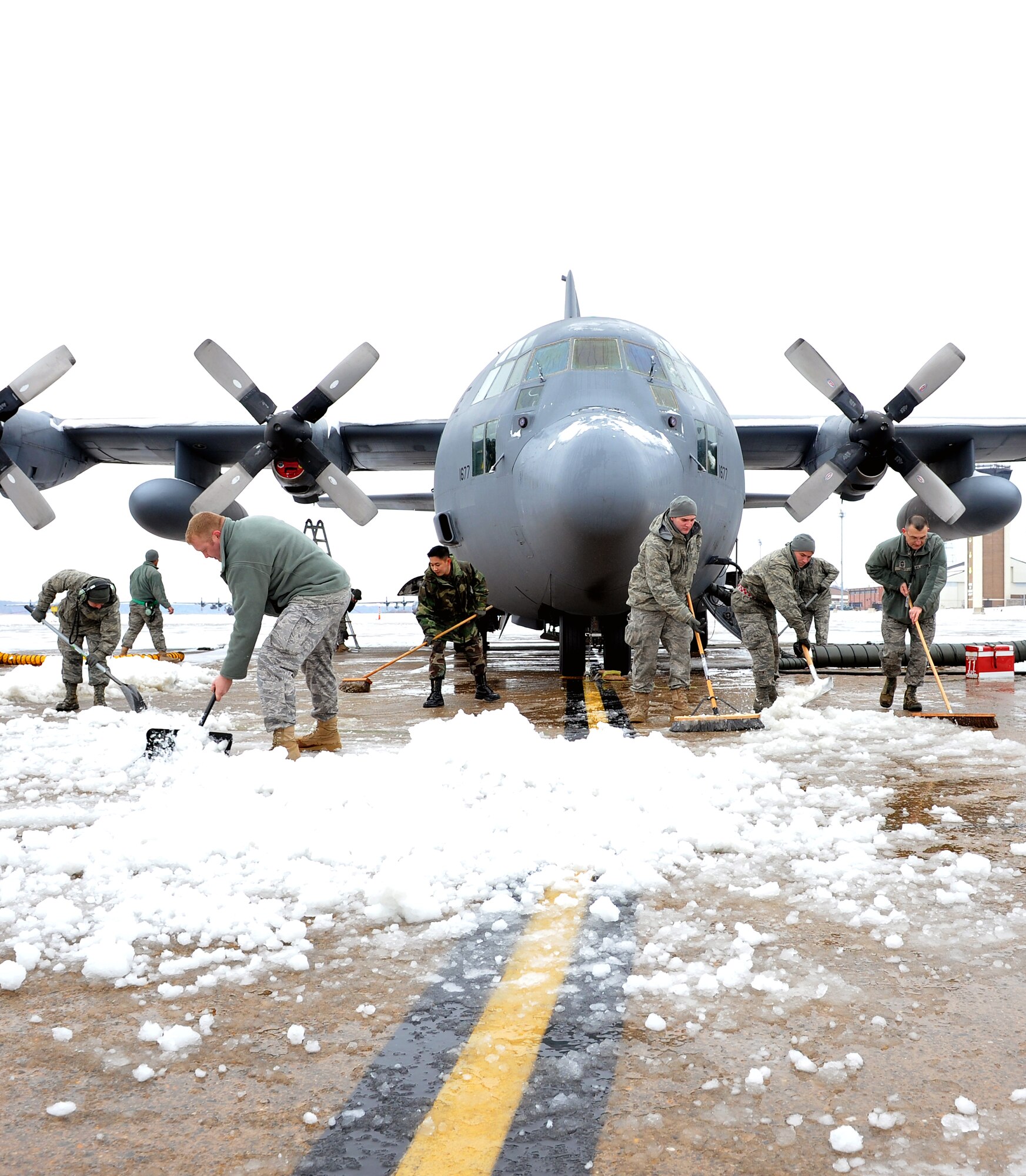 Members from the 19th Aircraft Maintenance Squadron shovel snow and ice away from a C-130 Hercules Jan. 10, 2011, on the base flightline. This day brought in the first snow of the new year at Little Rock Air Force Base, Ark. (U.S. Air Force photo by Staff Sgt. Chris Willis)