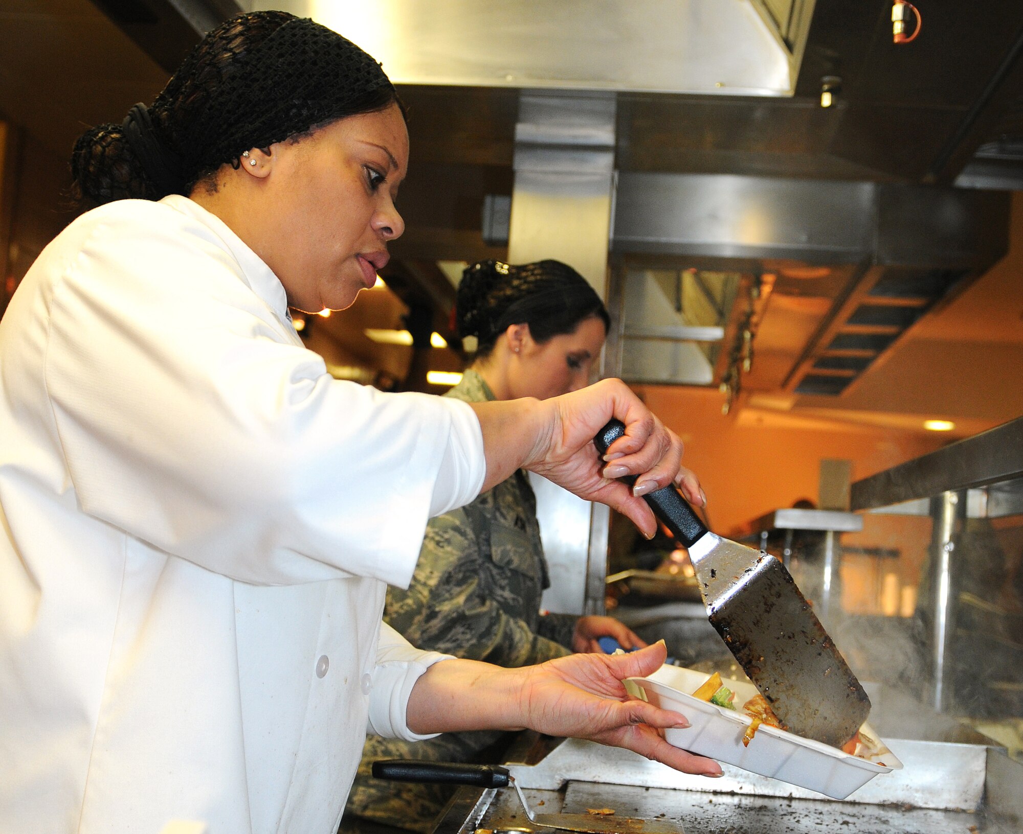 RAF MILDENHALL, England -- Rose St John, 100th Force Support Squadron Gateway Dining Facility head cook, places stir-fry in a to-go box Jan. 11, 2011 during a Mongolian Barbeque.  Next month, the dining facility will be visited by a committee to assess them for the Air Force Hennessy Evaluation. (U.S. Air Force photo/Senior Airman Tabitha M. Lee)