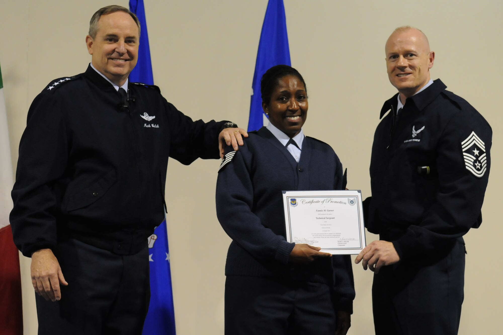 Gen. Mark A. Welsh III, U.S. Air Forces in Europe commander, and Chief Master Sgt. David Williamson, USAFE command chief, place new rank on the uniform of Fannie  M. Garner, 31st Force Support Squadron career development journeyman, promoting her to technical sergeant through the Stripes for Exceptional Performers program, during General Welsh's commander's call at Aviano Air Base, Italy, Jan. 10. This was General Welsh's first official visit to a USAFE wing since his assumption of command. (U.S. Air Force photo/ Staff Sgt. Nadine Y. Barclay)