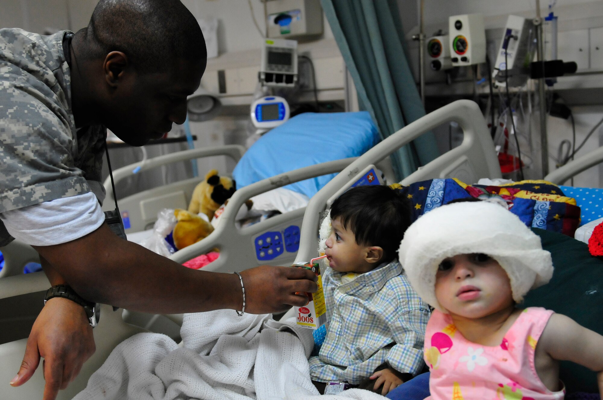 455th Expeditionary Medical Operation Squadron medical technican, Staff Sgt. Dequijamin Roberson attends to Ajamal  and Satara Hazrat, patients at the Craig Joint Theater Hospital at Bagram Airfield, Afghansitan, Jan. 10, 2011. A large majority of the Hazrat family were badly injured after the propane tank used to heat their home exploded. Ajamal's grandfather and aunt were treated here and all three have touched the hearts of the doctors and medics who interact with them each day. (U.S. Air Force photo by Senior Airman Shelia deVera)  